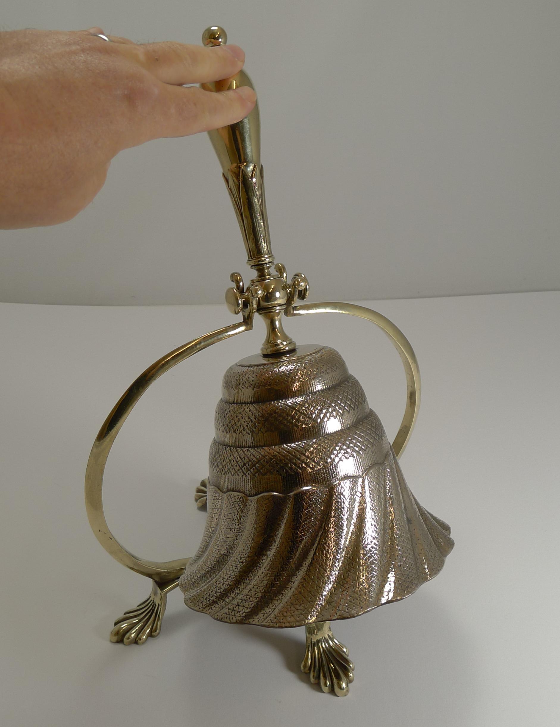 I have never seen anything quite like this before, a beautifully cast dinner bell to be used either in it's stand or hand-rung once removed from the stand.

Beautifully engineered, the stand and handle are made from a traditional brass and the