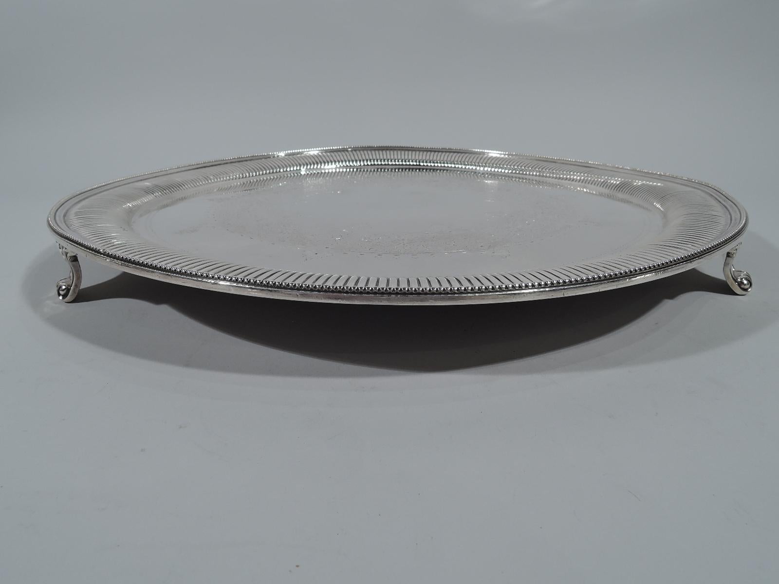 Victorian sterling silver salver. Made by Martin, Hall & Co. Ltd in London in 1892. Round with beaded rim and ribbed shoulder. Engraved strapwork wreath with flowers and foliage (center vacant). Three volute-scroll supports. Hallmarked. Weight: 60