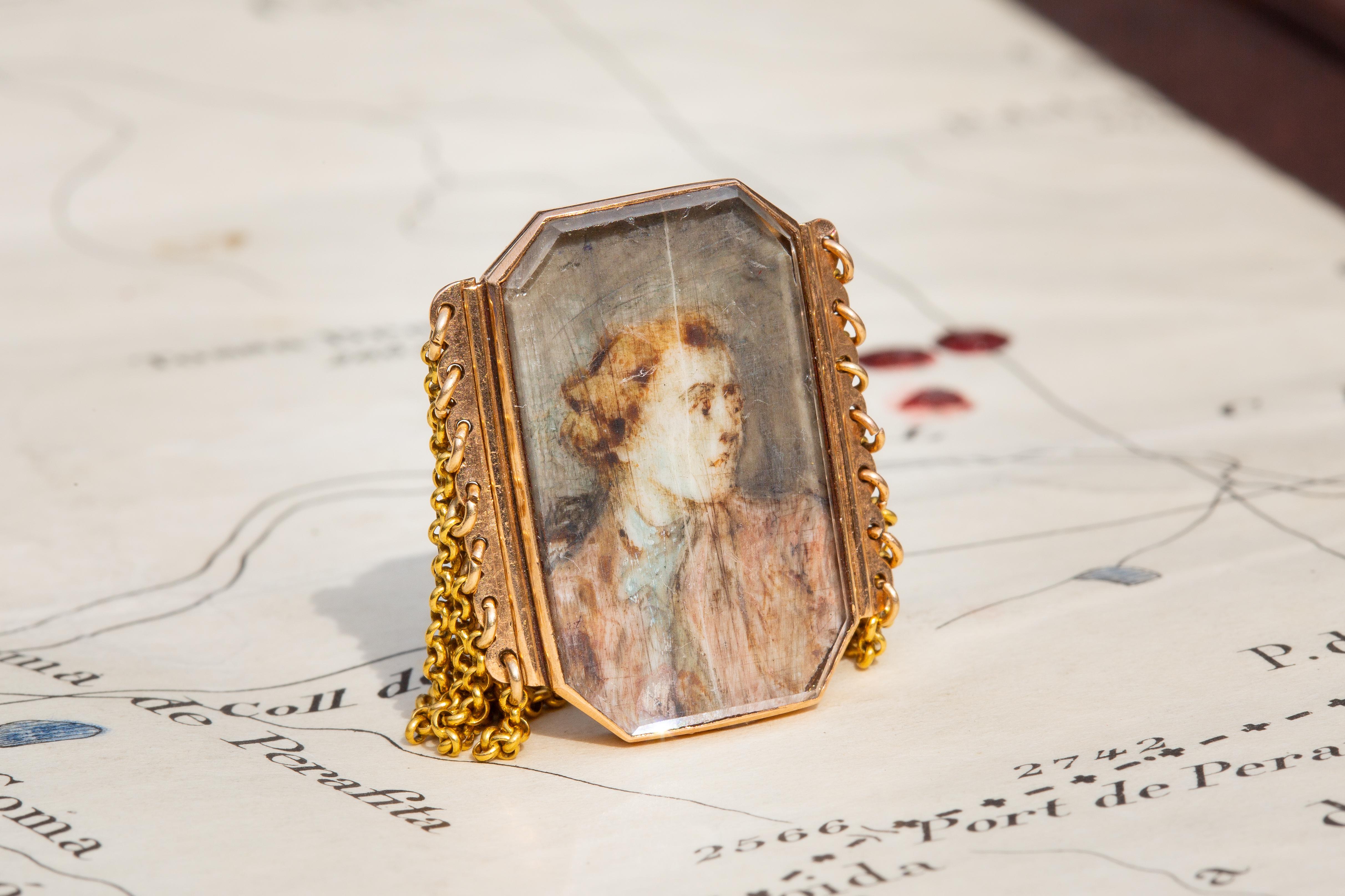 This highly unusual antique gold ring features a late 18th century French portrait miniature attached to a multi-strand belcher-link chain. 

Portrait miniature rings were, for the most part, of a sentimental nature; commissioned and worn by loved