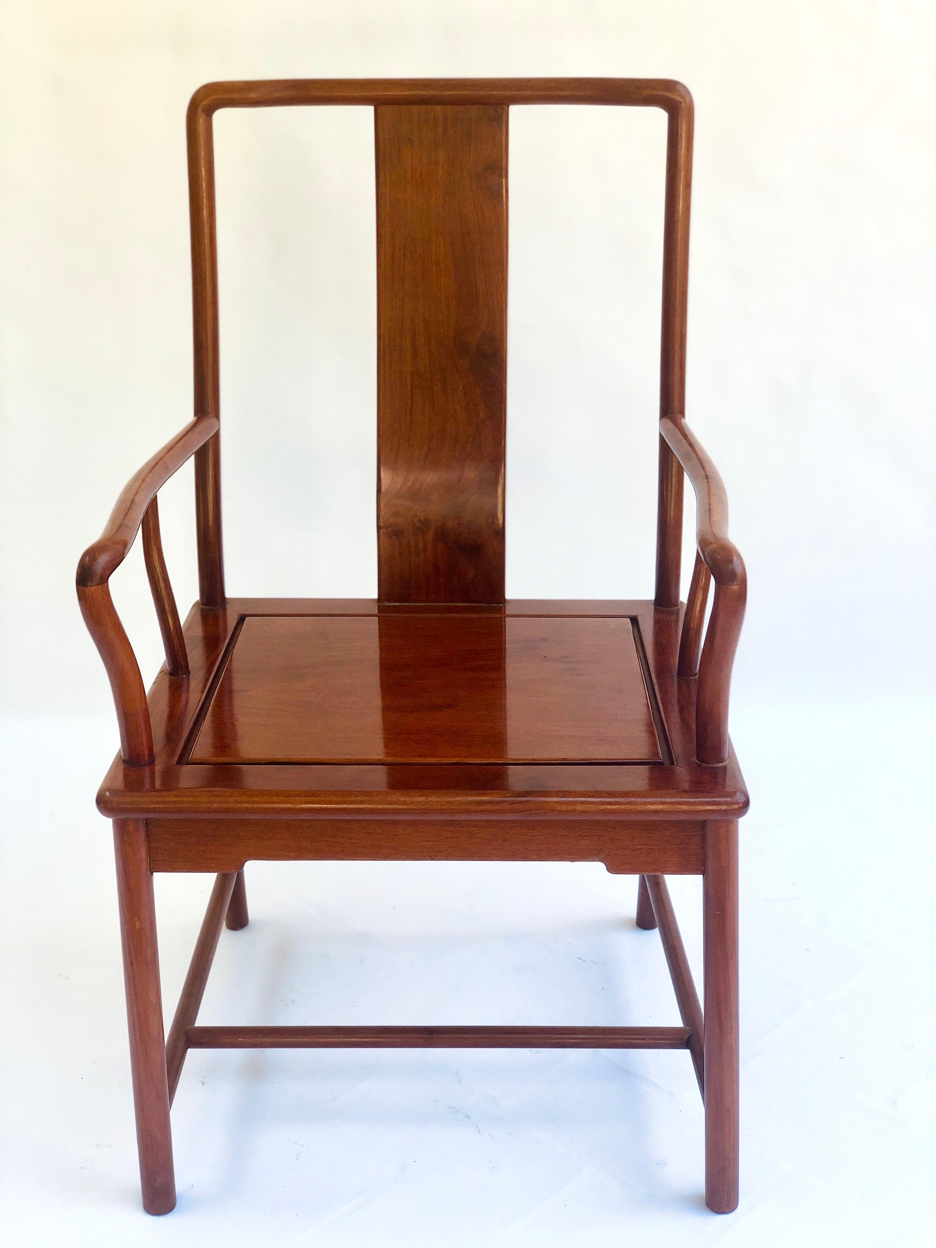 Unusual antique hardwood Chinese armchair. This chair has a delightful design with a beautiful rich tone. It boasts an attractive centre splat to the back and elegant shaped open arms with a hardwood seat. It is raised on turned legs united by