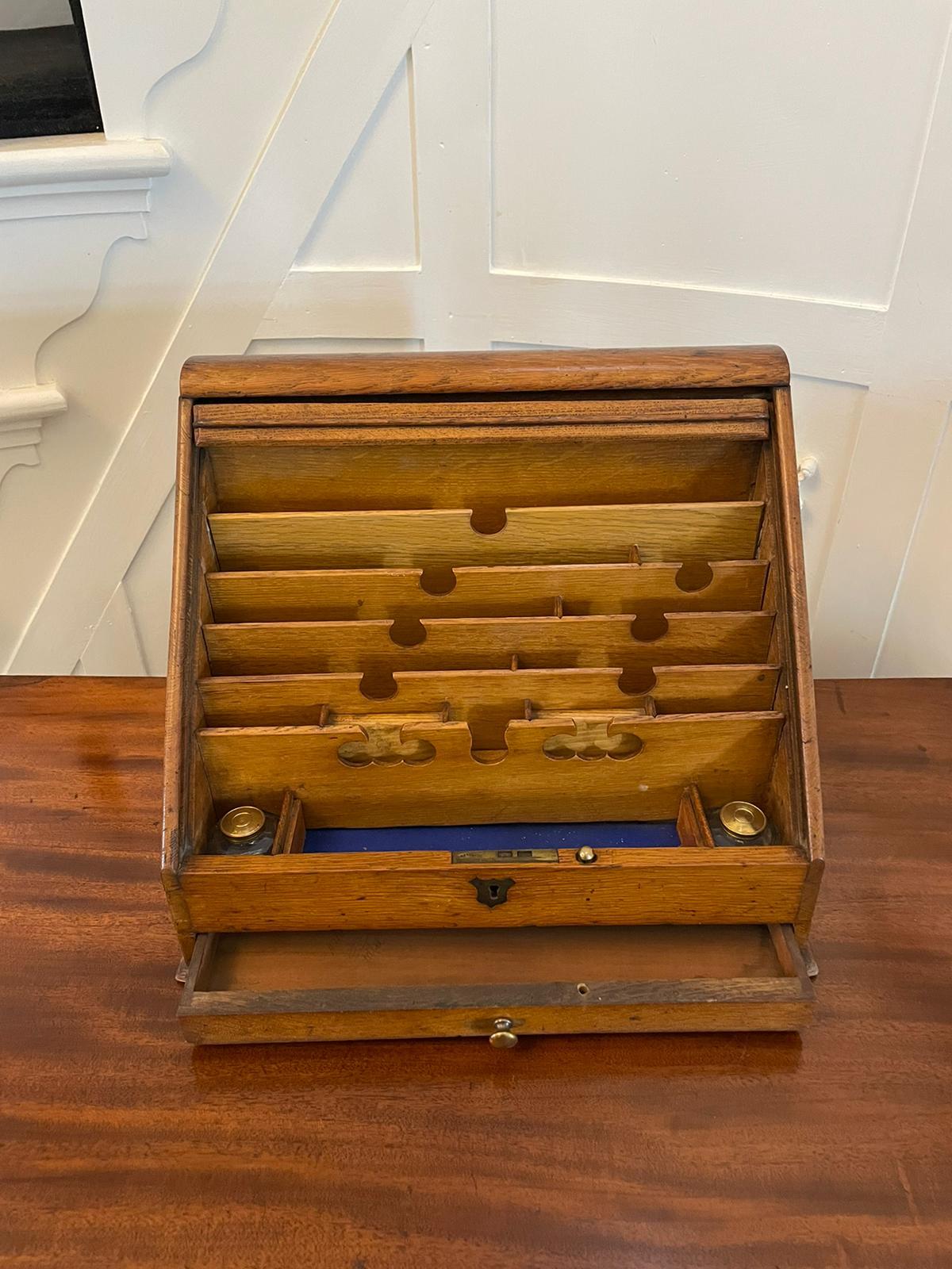 Unusual antique oak stationery cabinet with a sliding tambour front opening to reveal a fitted interior, original brass top ink bottles and a pop out drawer.

A quaint piece in lovely original condition.

Dimensions:
Height 31 cm (12.2