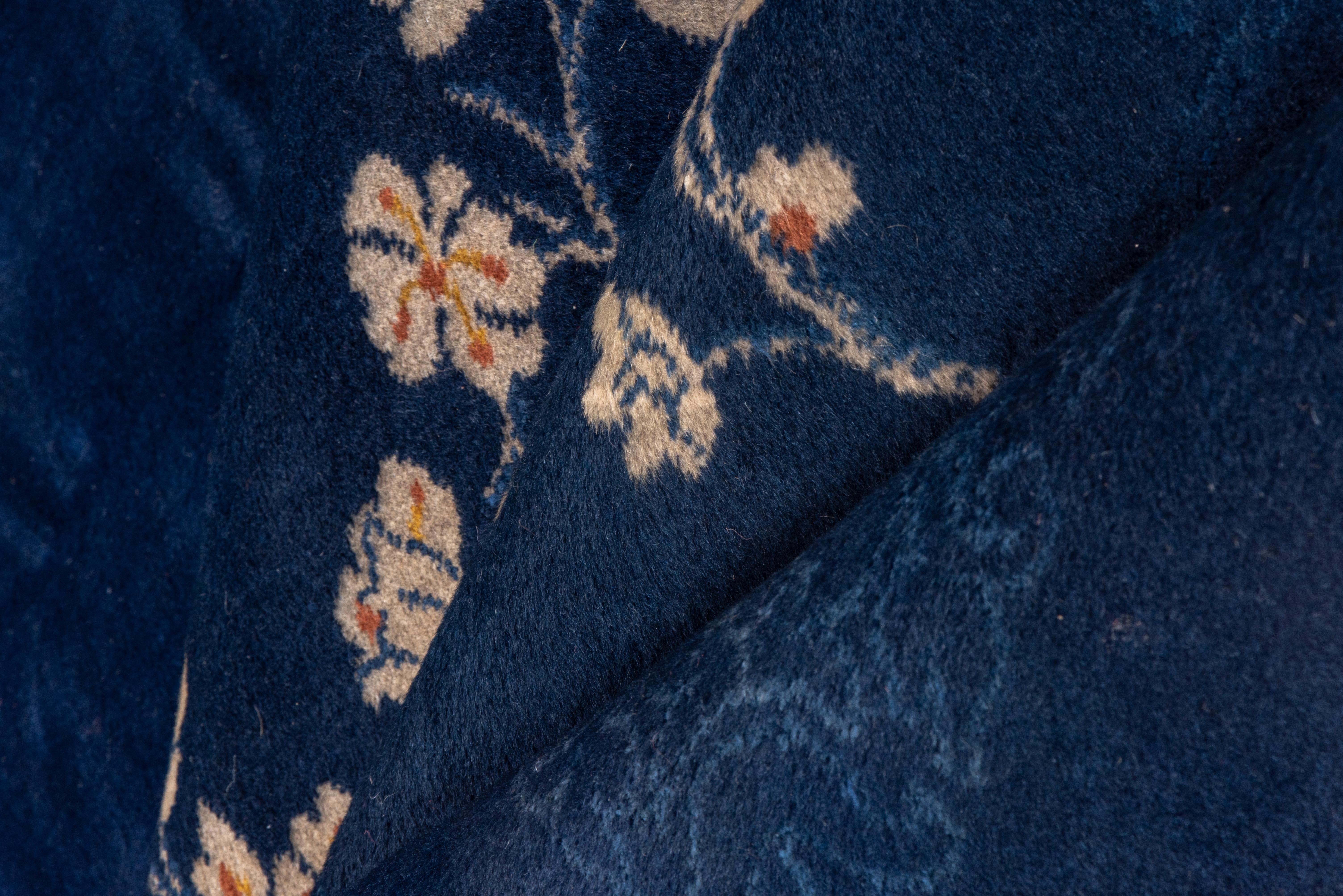 This Art Deco Tianjin interwar carpet features a dark and royal blue palette with only two asymmetric floral spray corners as field decoration. Blue-on-blue floral palmette border. Good condition. Restrained elegance with a saturated color