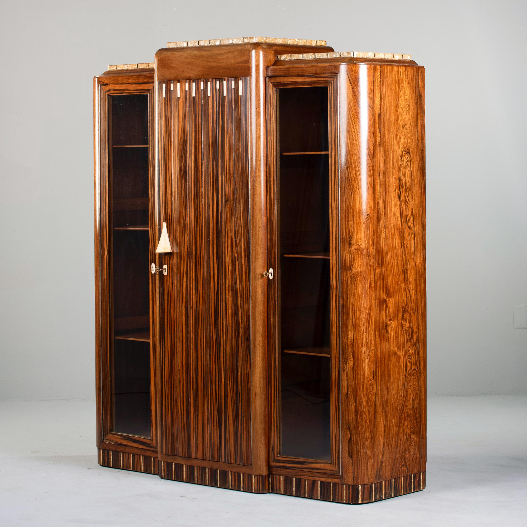 Found in France, this Art Deco macassar cabinet dates from the 1930s. Center section of cabinet has four fixed internal shelves. Door handle features bone overlay and the top of the door features decorative bone inlay and bone-trimmed escutcheons.