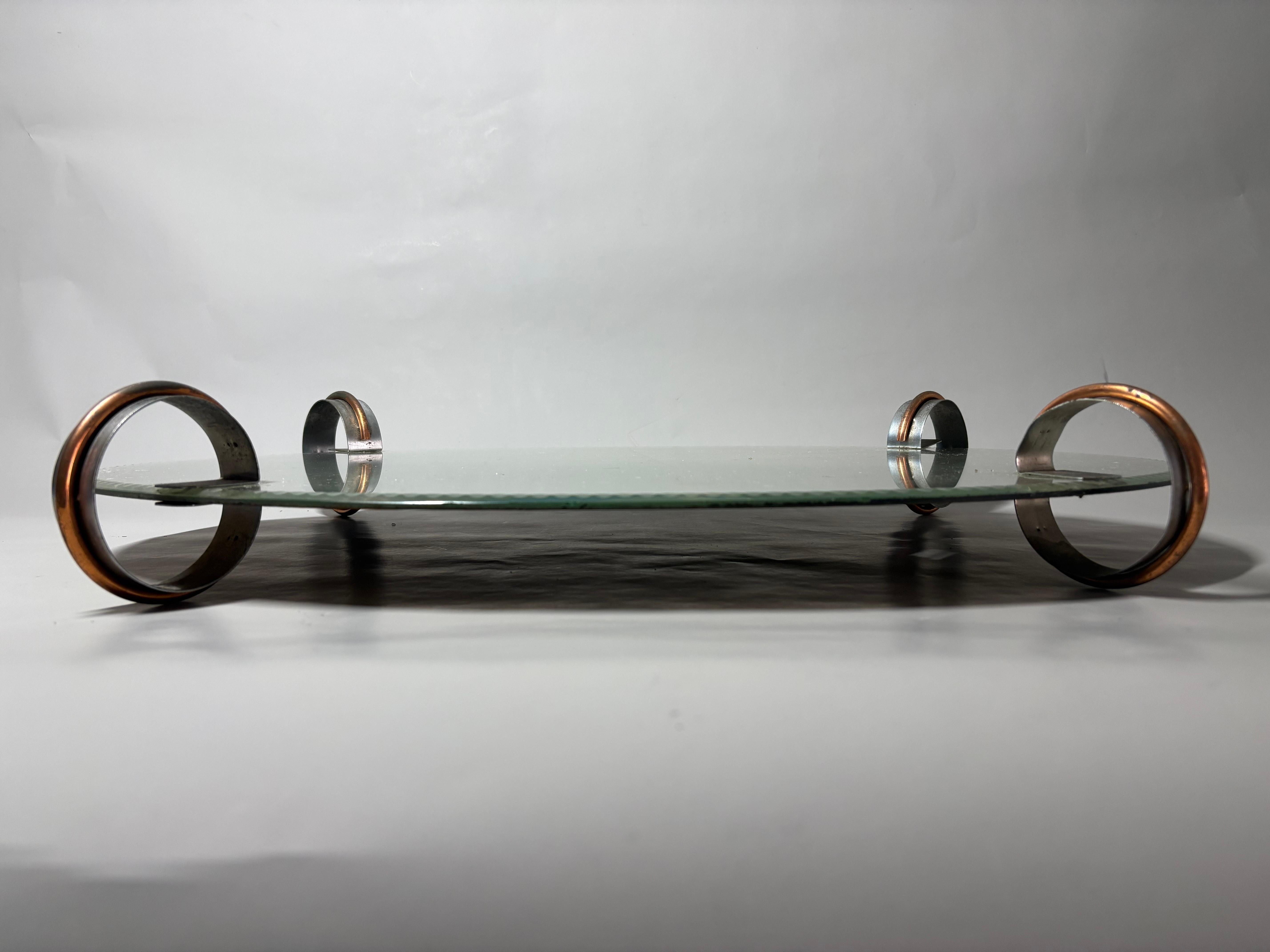 Un Surtout-de-table / meseta espejada / centro de mesa de época Art Decó, difícil de encontrar e inusual, de hacia 1935. La meseta ovalada espejada se eleva sobre pies circulares de metal bicolor.
Muy probablemente francés.

El espejo y las patas