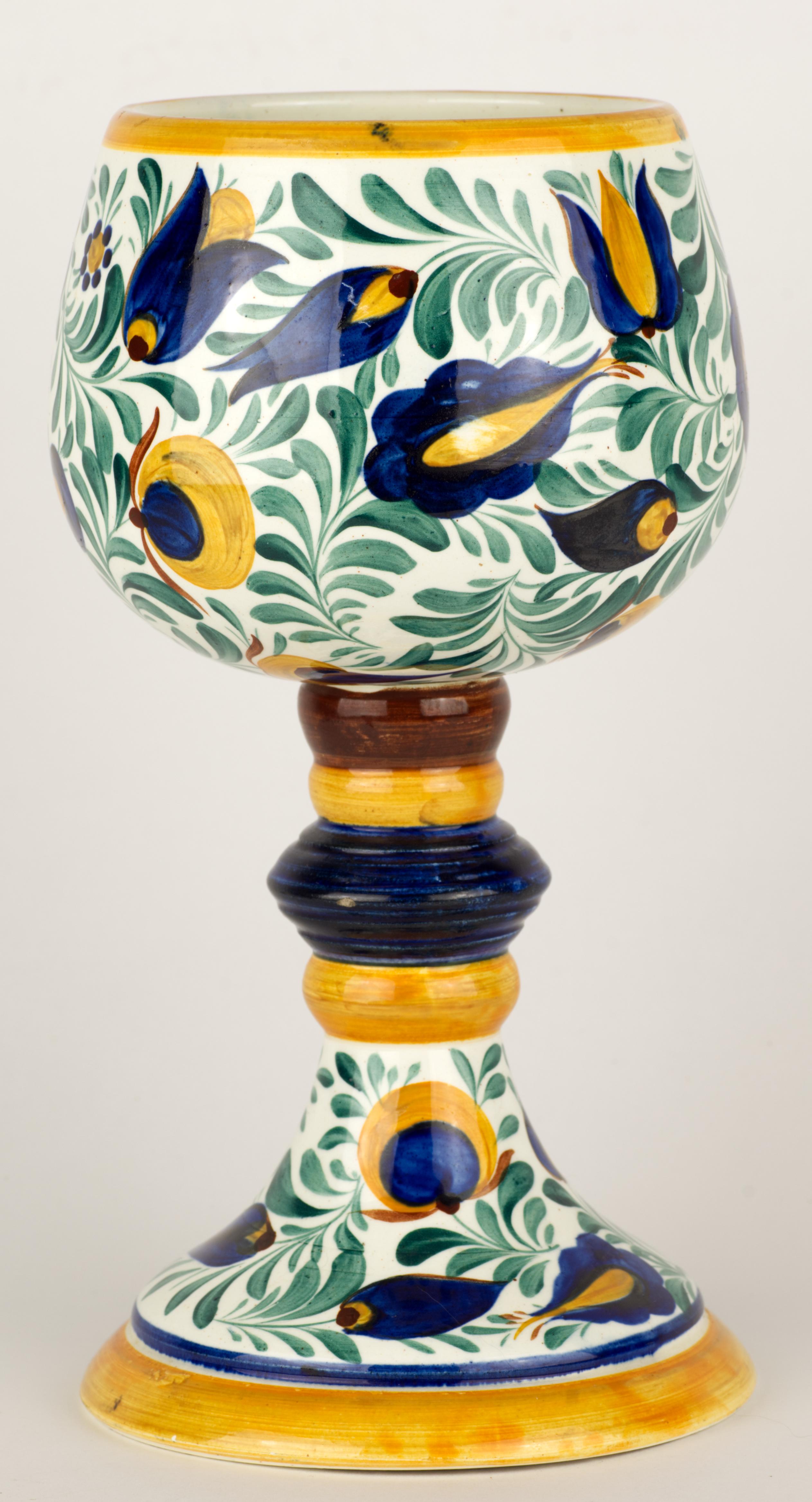  L'insolito vaso alto a forma di calice è stato decorato a mano con un complesso motivo floreale astratto in blu cobalto, giallo marigold e verde salvia sulla base e sul corpo del vaso. Il piede molto dettagliato è colorato con smalti blu, gialli e