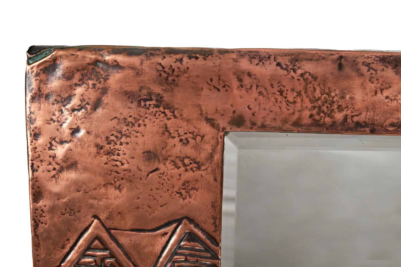 Fine And Unusual Arts & Crafts Rectangular Copper Wall Mirror having a beveled edge mirror with an ornate copper frame with raised decoration of a coach and horses to the bottom corner and a man in the moon raised decoration to the top corner.