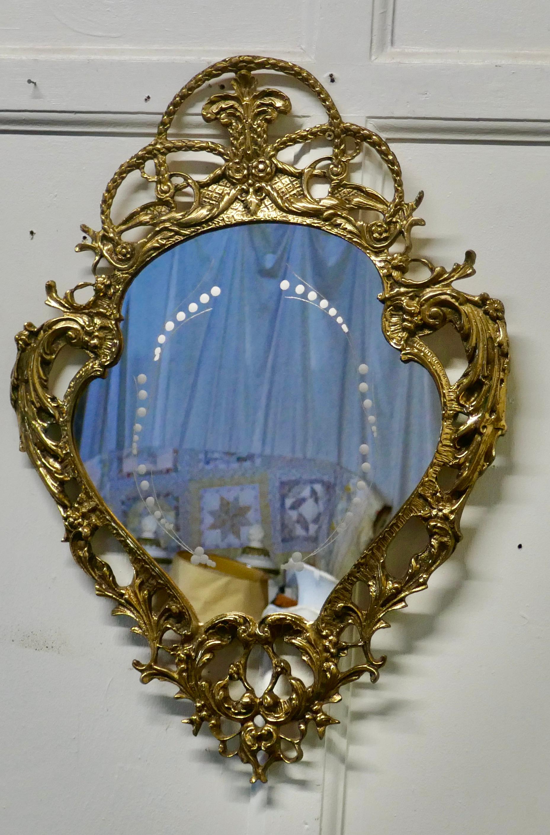 Unusual brass filigree mirror with etched glass pattern

A very attractive piece with an unusual shape and decorative brass frame
The mirror itself has a dainty beaded etched design
The mirror is in good condition, it is 26” tall and 19”