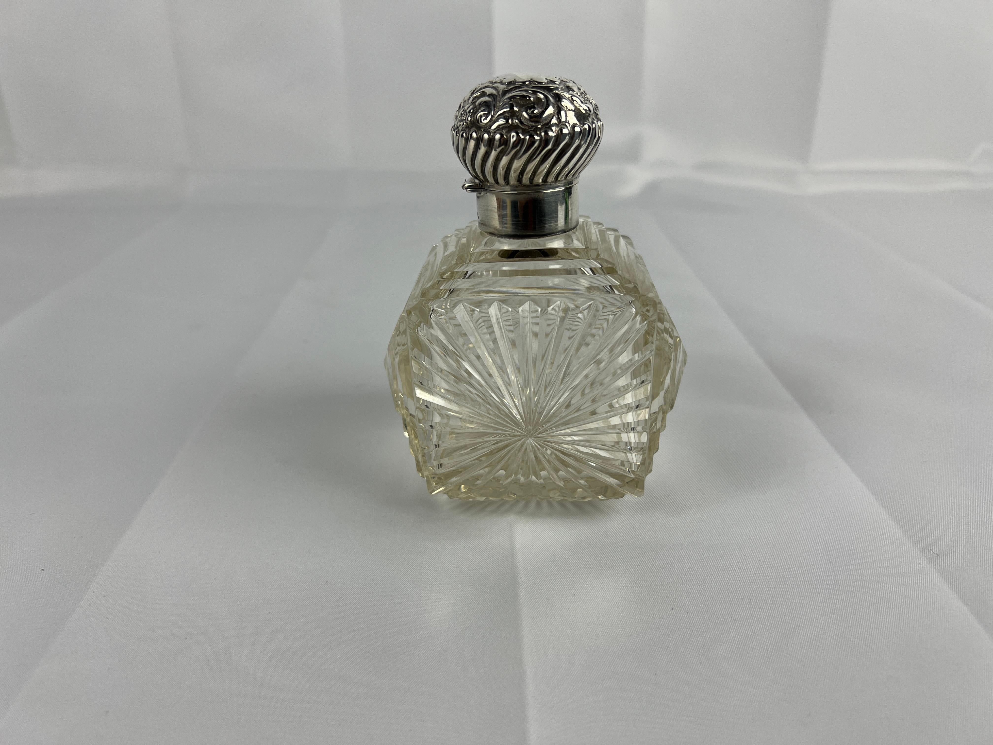Questa squisita bottiglia di profumo britannica in argento sterling e vetro tagliato è un pezzo raro ed elegante, che combina un'intricata lavorazione artigianale con un design senza tempo. La bottiglia presenta un corpo in vetro soffiato a mano,