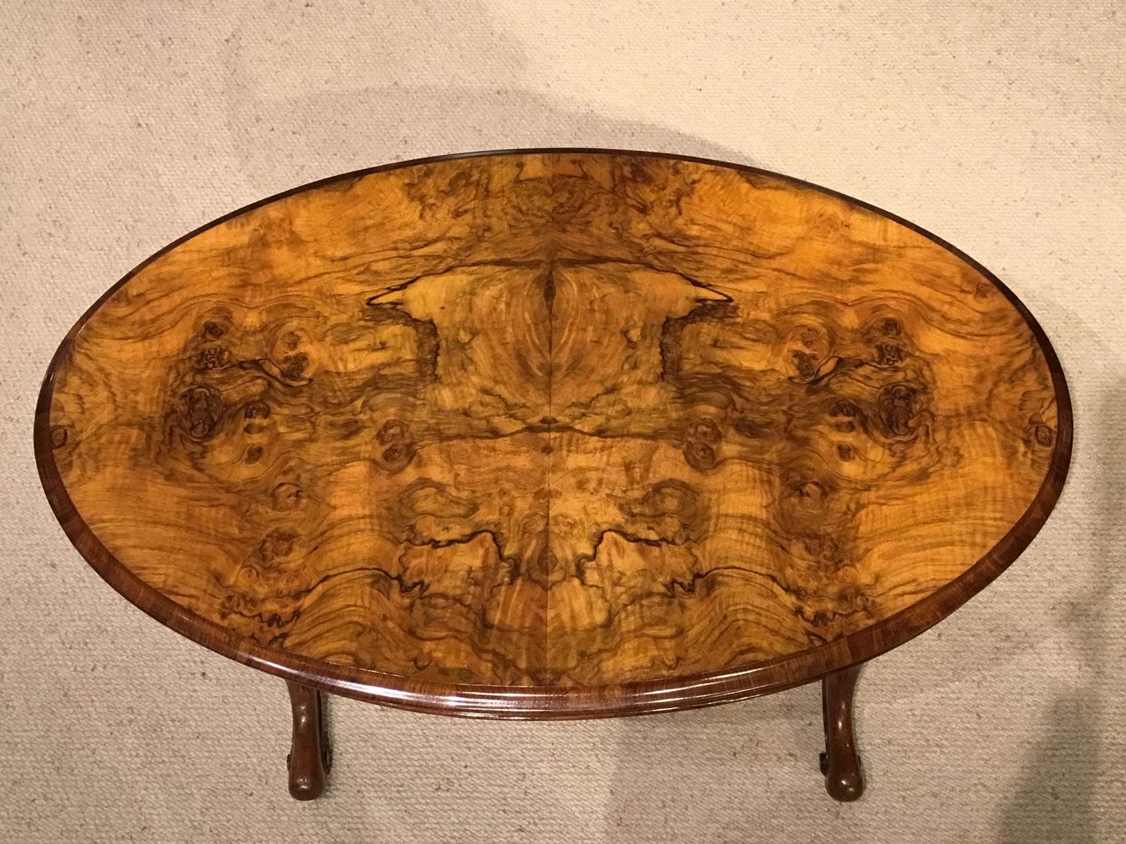 An unusual burr walnut and walnut Victorian period oval coffee table with slide. Having an oval top veneered in beautifully figured burr walnut with an unusual sliding shelf with an inset green gilt tooled leather. Supported on turned and carved
