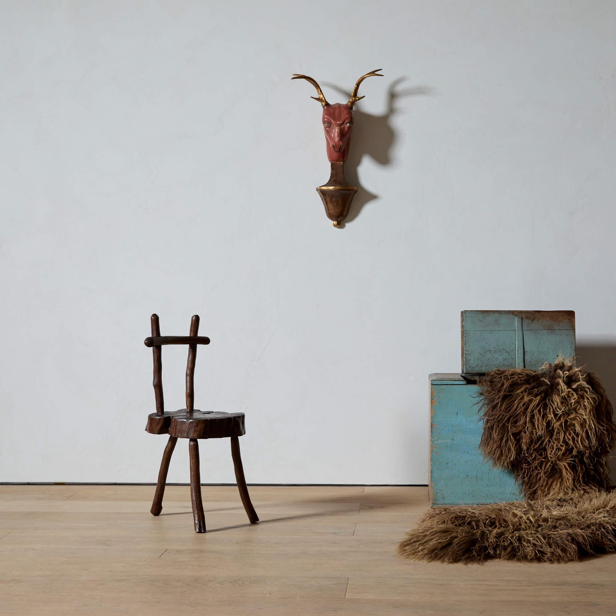 Dieser aus Holz geschnitzte Hirschkopf ist eine lebendige Bereicherung für jeden Raum. Er ist mit fein gegossenen und vergoldeten Metallhörnern, abgenutzten ziegelroten Pigmenten und einem Ausdruck grimmiger Konzentration verziert. Sie sitzt auf