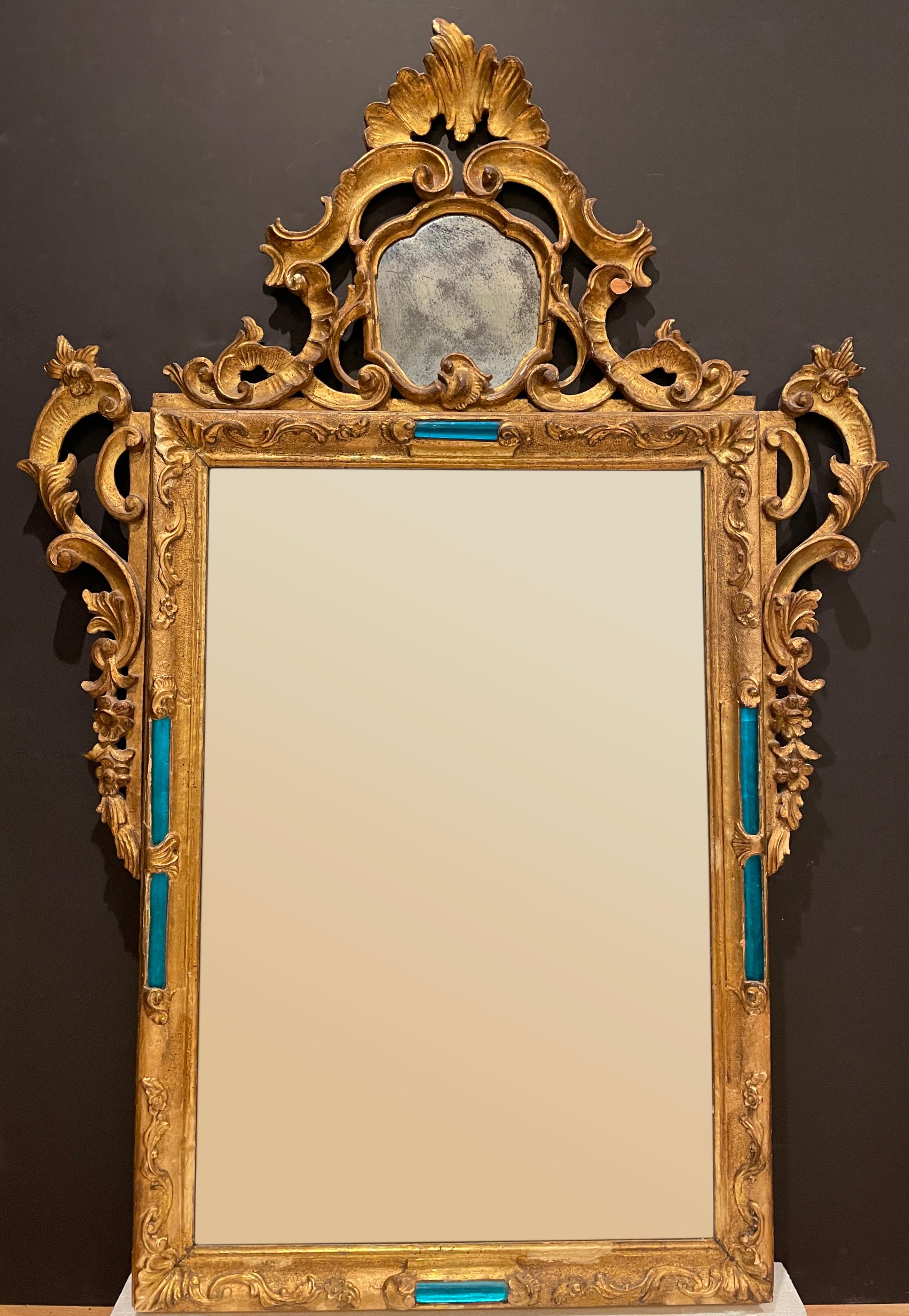Highly unusual 19th century Baroque Rococo Venetian carved giltwood mirror. Featuring two mirrored panels and aqua blue/blue blown glass inset rods and original mirror with areas of spotted silvering losses.
