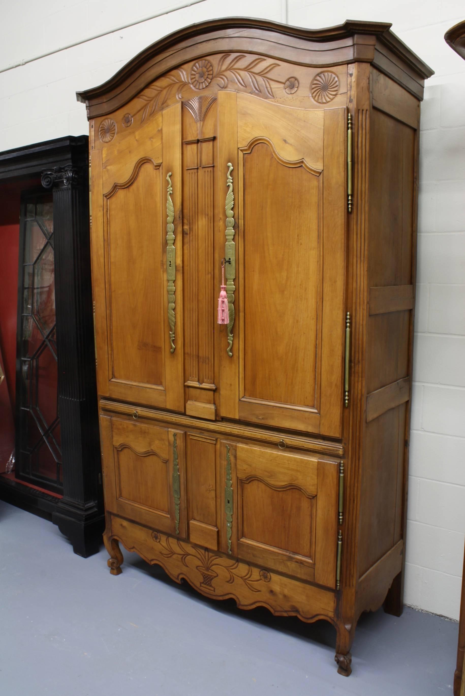 This unusual cherry cupboard or armoire from Brittany features four doors with a pull-out shelf separating the upper and lower sections. The upper sections features a pair of nicely carved columns, surmounted by a very finely carved wheat sheaf. The
