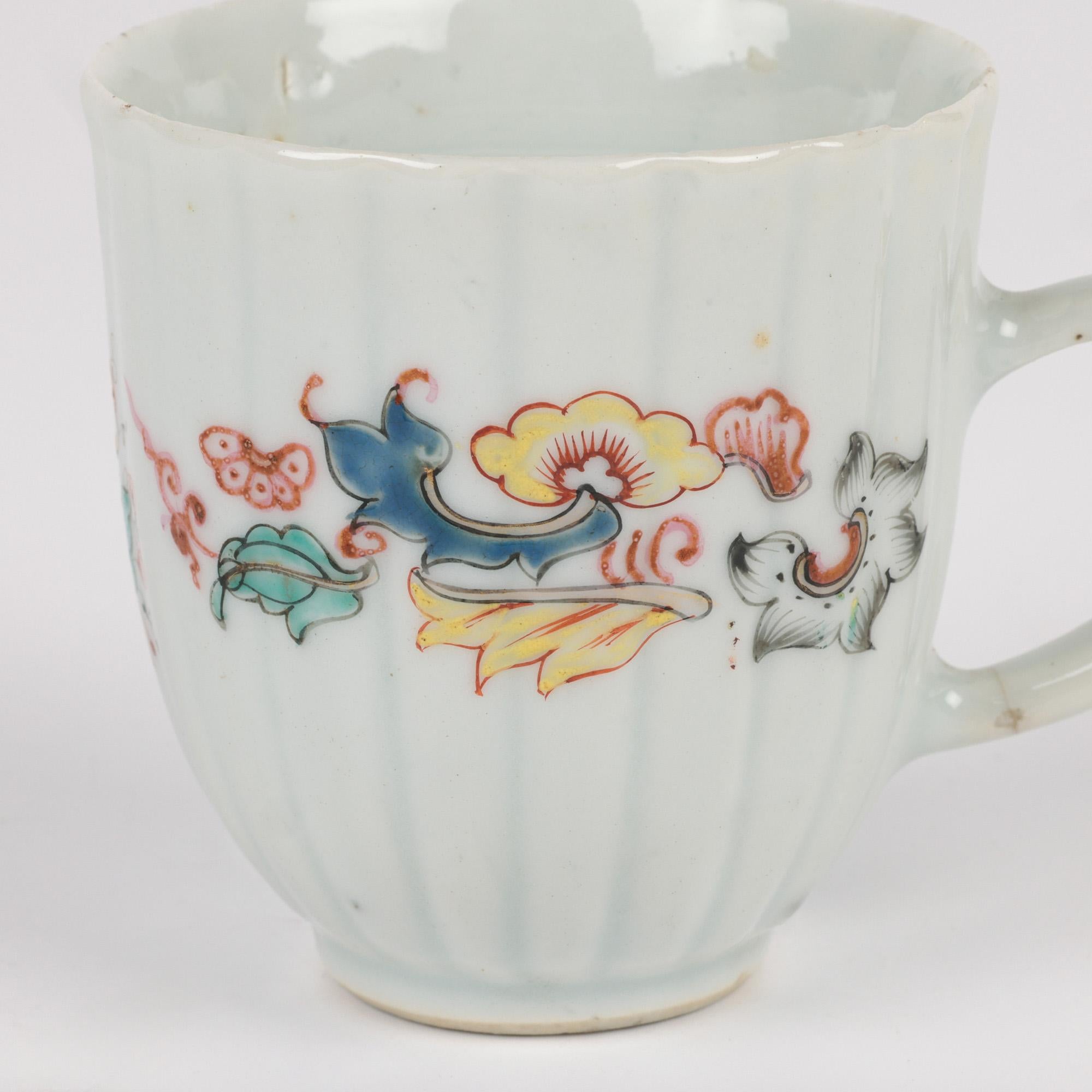 A very fine and unusual antique Chinese porcelain teacup hand painted in coloured enamels and dating from Yongzheng reign 1723-1735. The white glazed cup has a tall round ribbed body with a looped handle applied to one side and is hand painted with
