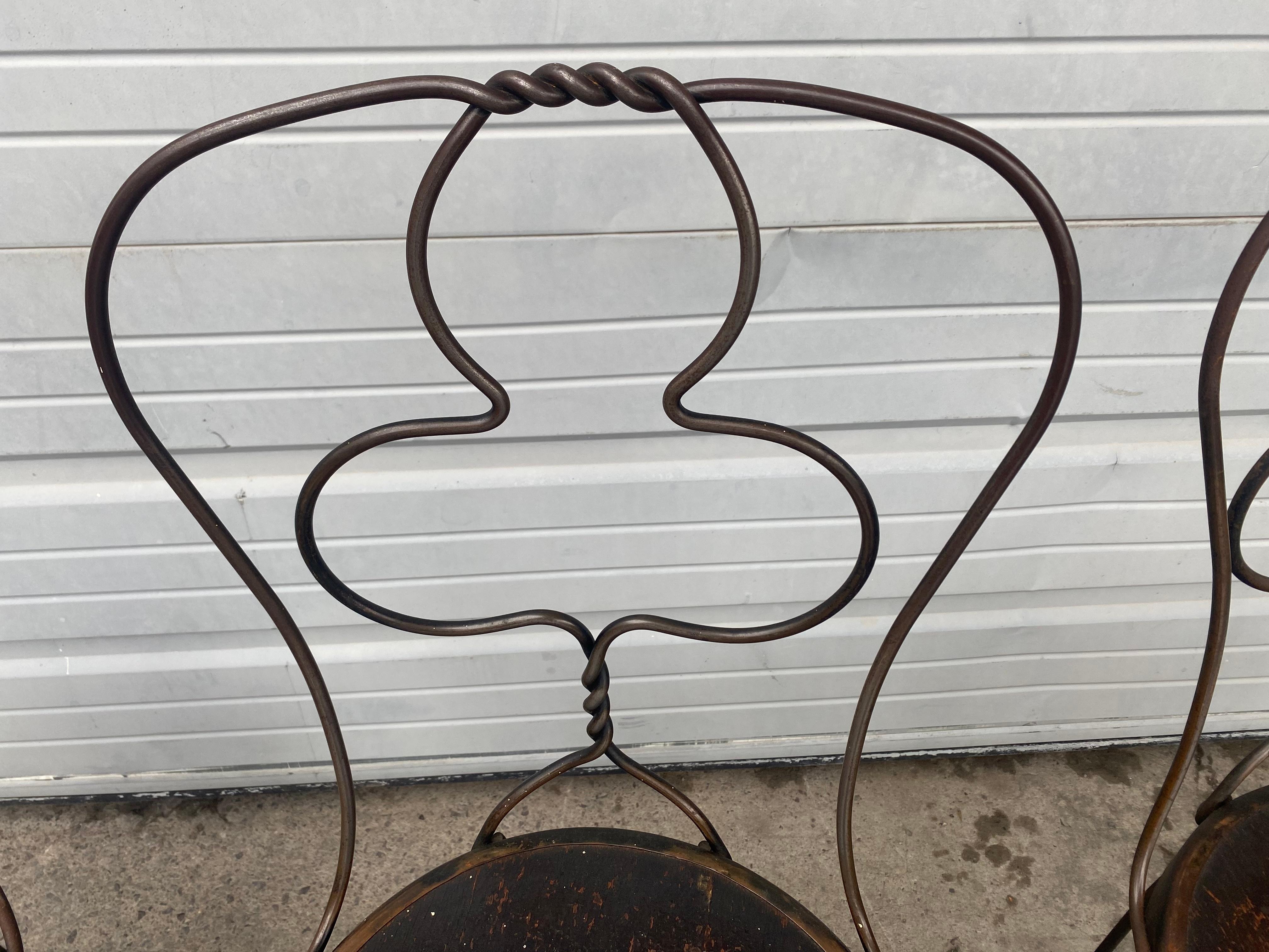 Unusual set wrought iron ice cream parlor chairs, bistro chairs, a set of 4. Wrought iron metal frames, twisted backs and legs. Amazing seldom seen club back design as well as twisted iron center finial. Wonderful original patina /finish.
 