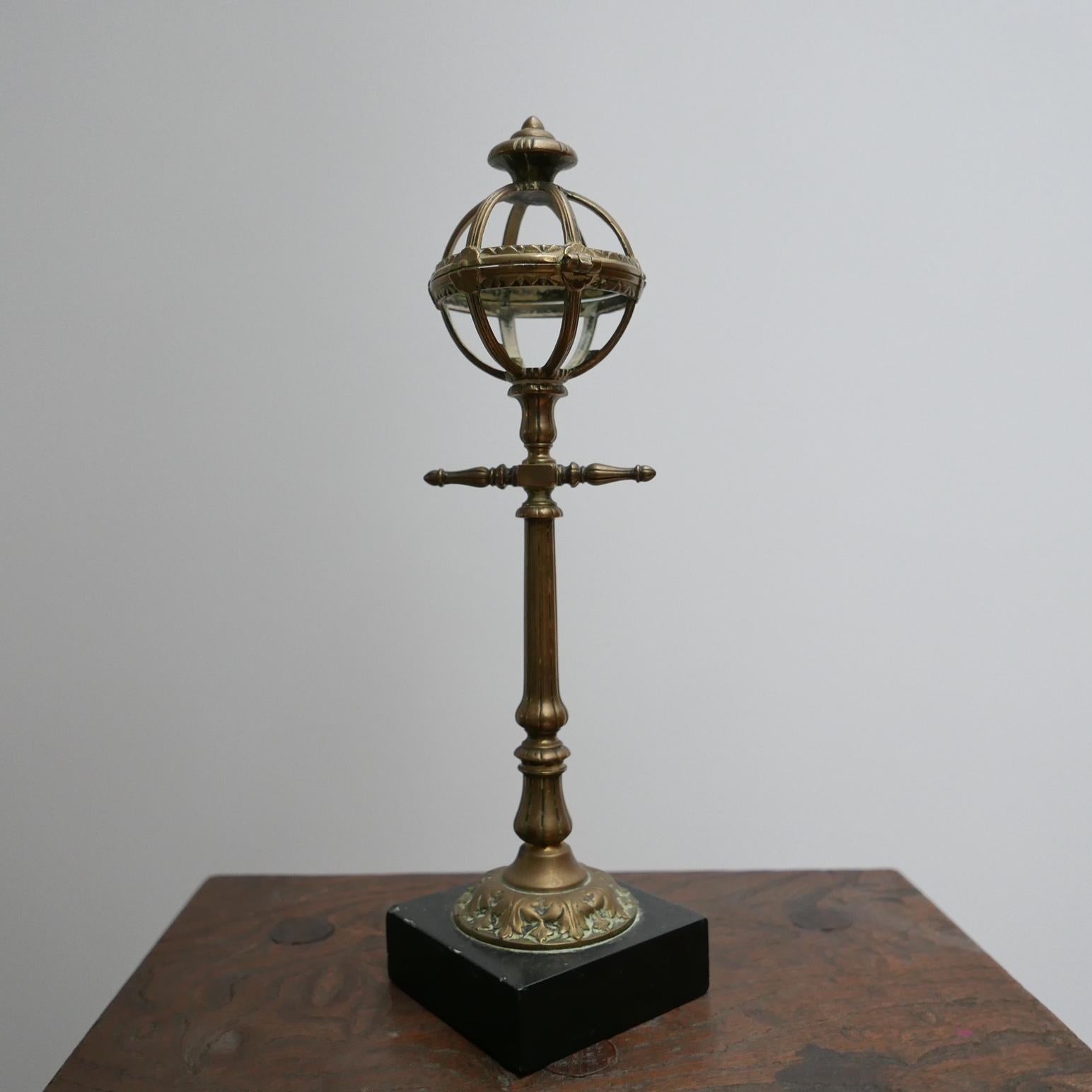 An unusual brass desk top, mantelpiece or shelf curio. 

Likely England or France, c1900s. 

Raised over a black marble bass, this details desk top model of a street lantern has a hinged lid. 

Location: London Gallery. 

Dimensions: 32 H x