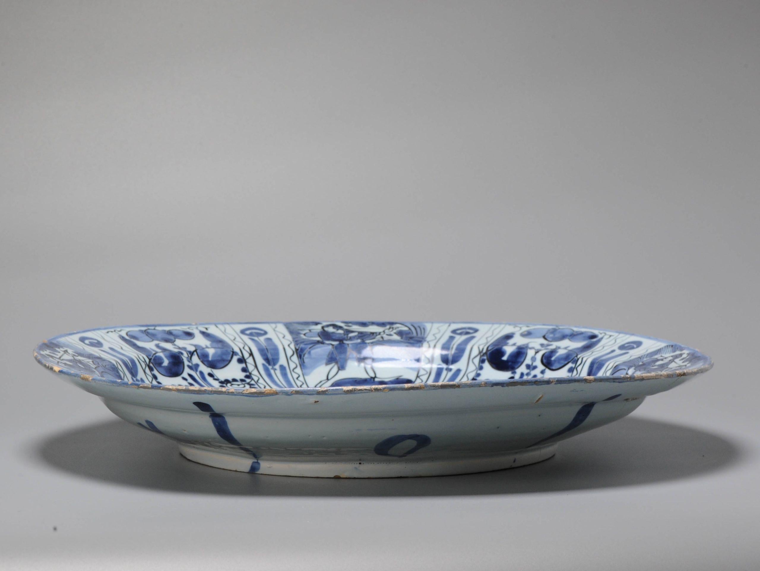 Earthenware dish on footring. flat rim. Decorated in different shades of blue on a white tin glaze in Chinese Transitional style with the so called 'Lion of Juda' in a garden landscape. Flower scrolls replace the diaper motif as a border around the