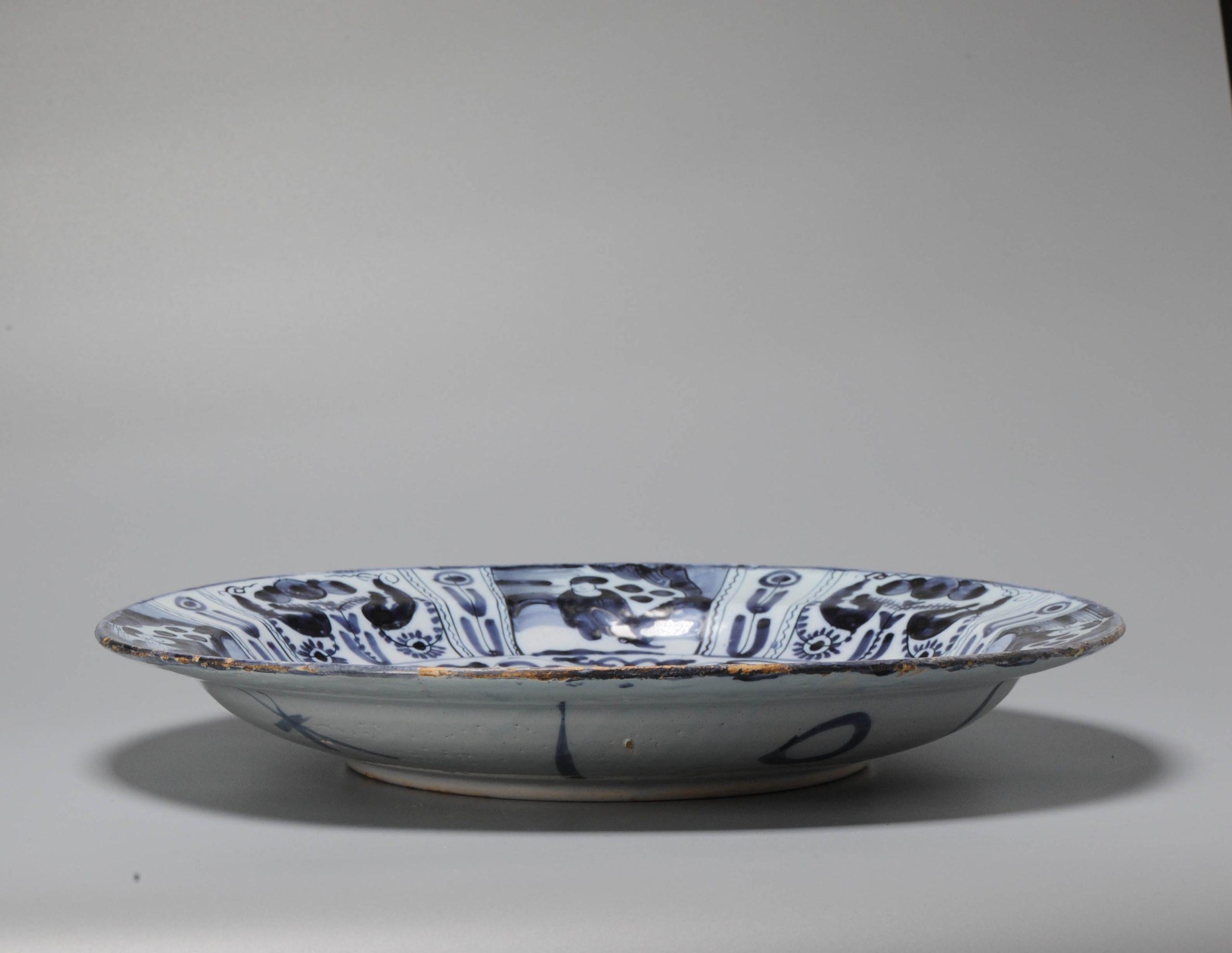Earthenware dish on footring. flat rim. Decorated in different shades of blue on a white tin glaze in Chinese Transitional style with the so called 'Lion of Juda' in a garden landscape. Flower scrolls replace the diaper motif as a border around the