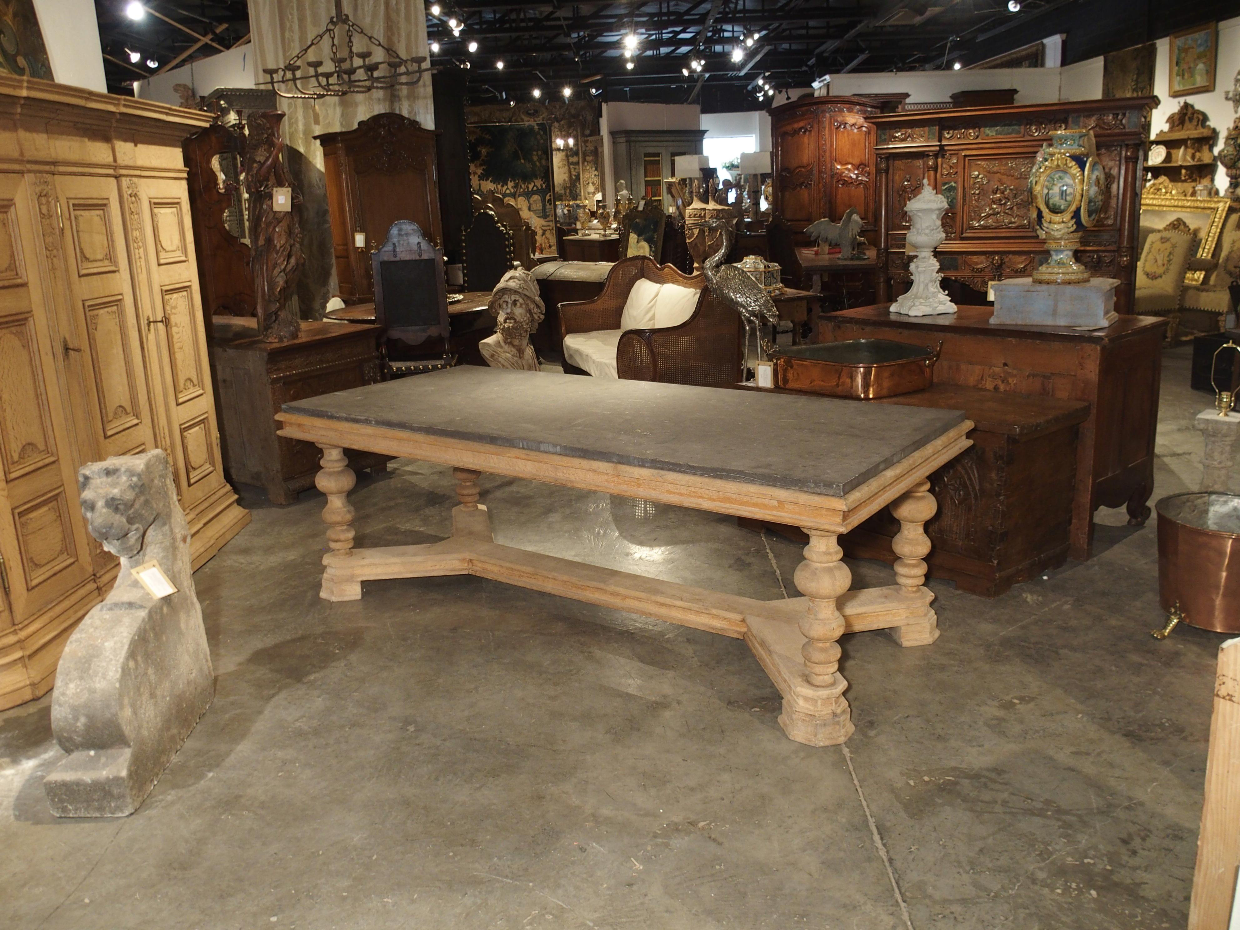 This fantastic oak table comes from very far Northern France or Southern Belgium.  It was used as a display table in a pastry shop or Boulangerie.  The top is a thick bluestone slab, which rests on over a unique oak wood base.  Beneath the stone, is