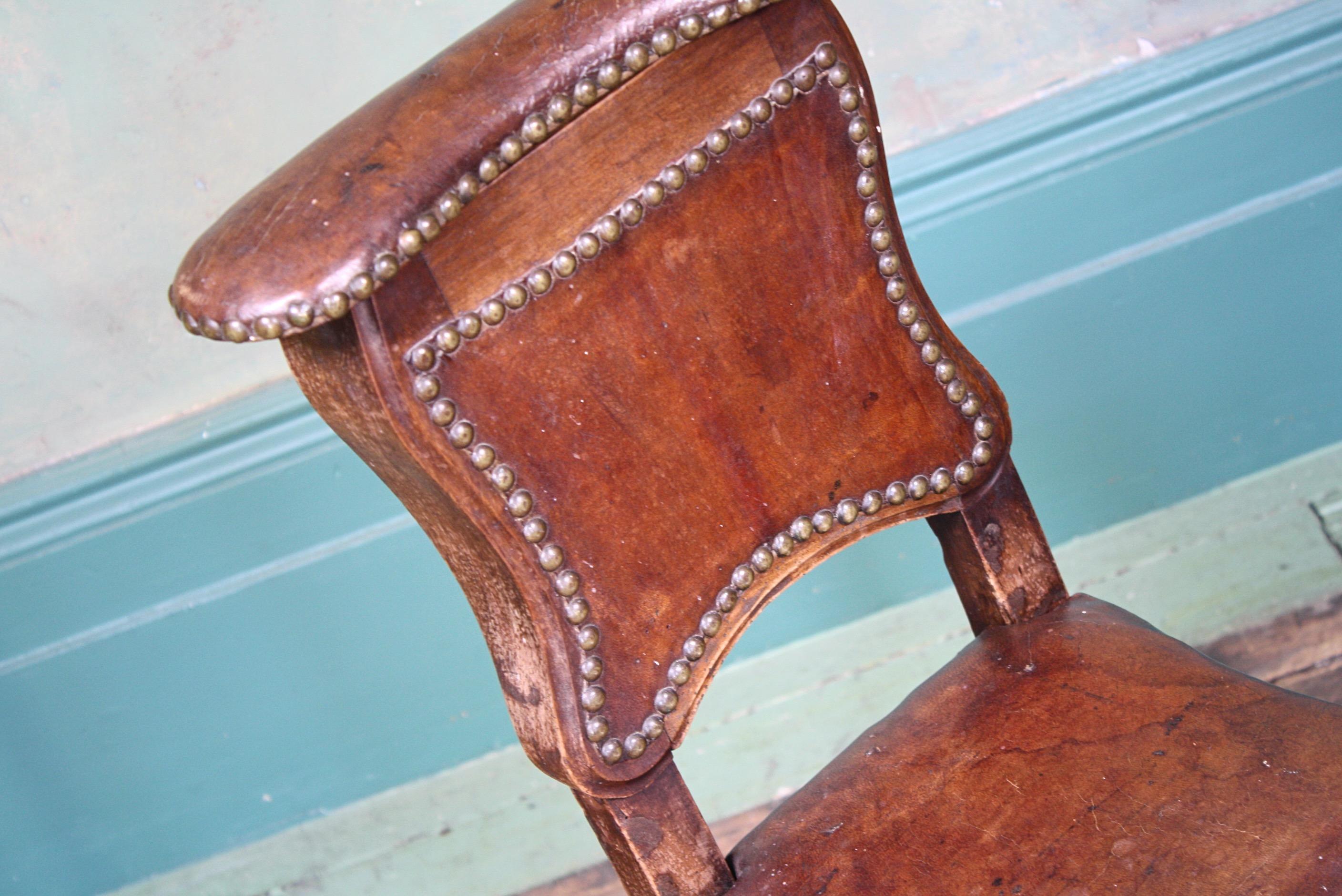 A shapely early 19th century leather and oak chair, upholstered with its original conker brown leather and stud work. 

The chairs original use was to wash from, the seat is removable and would off housed a ceramic bowl. Also the small decorative
