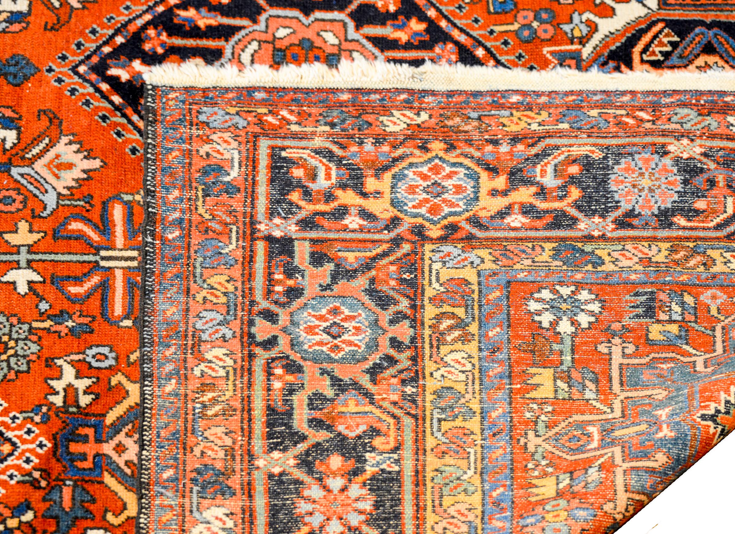 An unusual early 20th century Persian Heriz rug with twenty-one stylized floral medallions woven in light and dark indigo, gold, crimson, and white vegetable dyed wool, on a gorgeous bold crimson background. The border is wide, with a large central