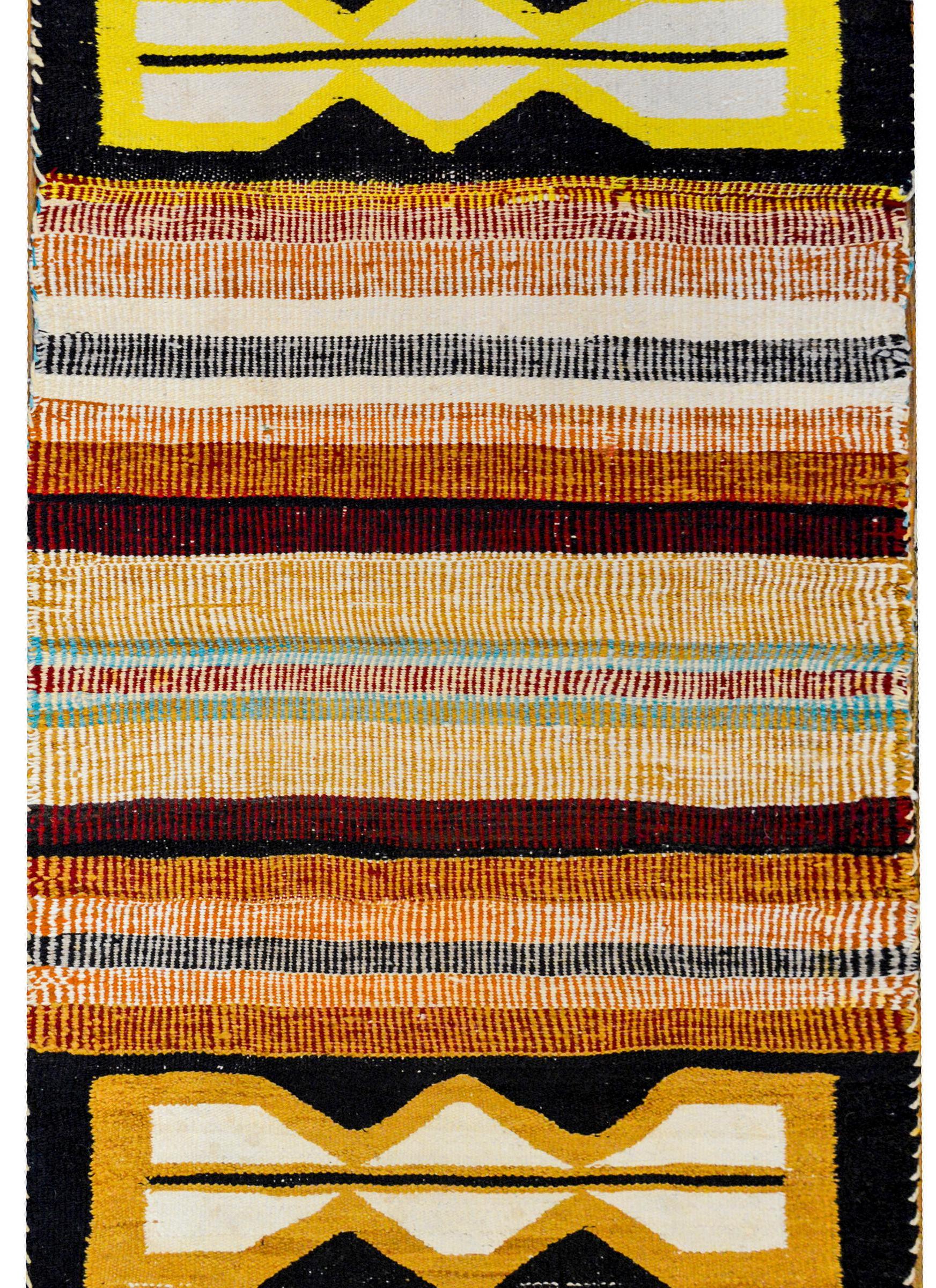 An unusual 20th century Native North American Navajo rug with a wonderful bold striped pattern woven in natural rust, green, gold, deep red, and white colors, with two large geometric patterned shapes on each end.