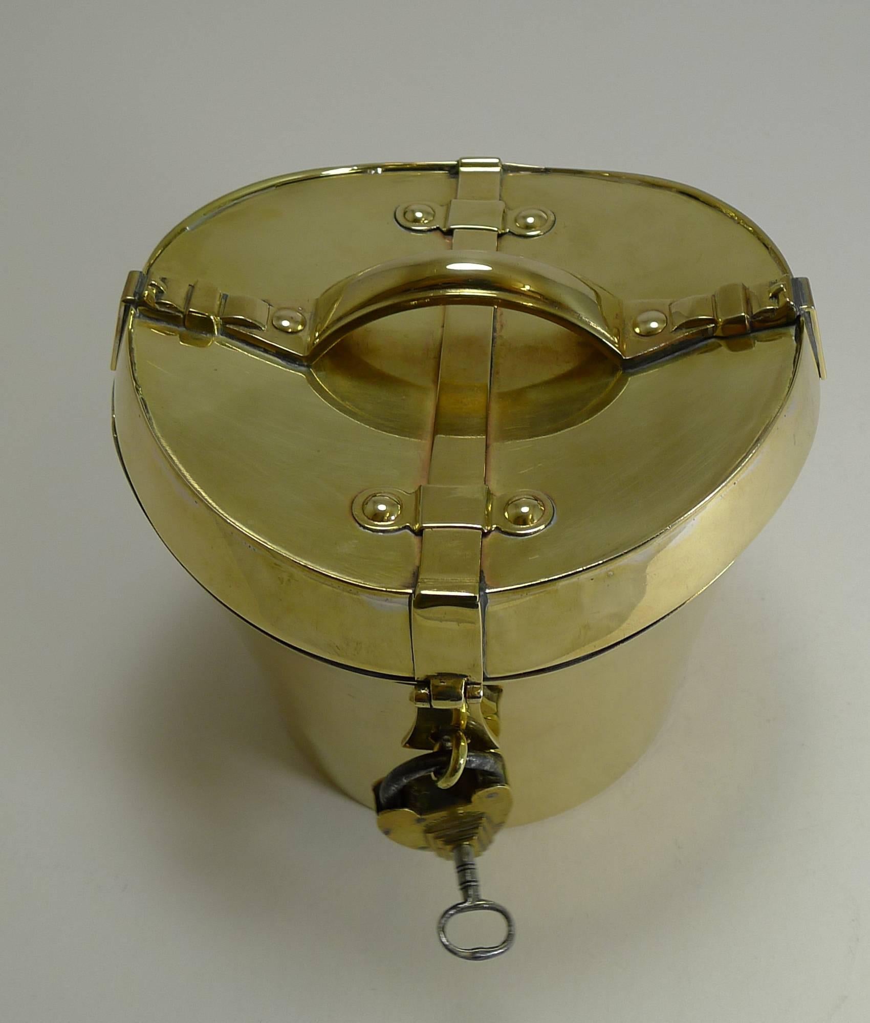 A highly sought-after and collectable brass biscuit box in the form of a Hat Box with an integral handle to the top and belt and buckle detail to either side just like a leather hat box.

The front has a working padlock and key and once opened the