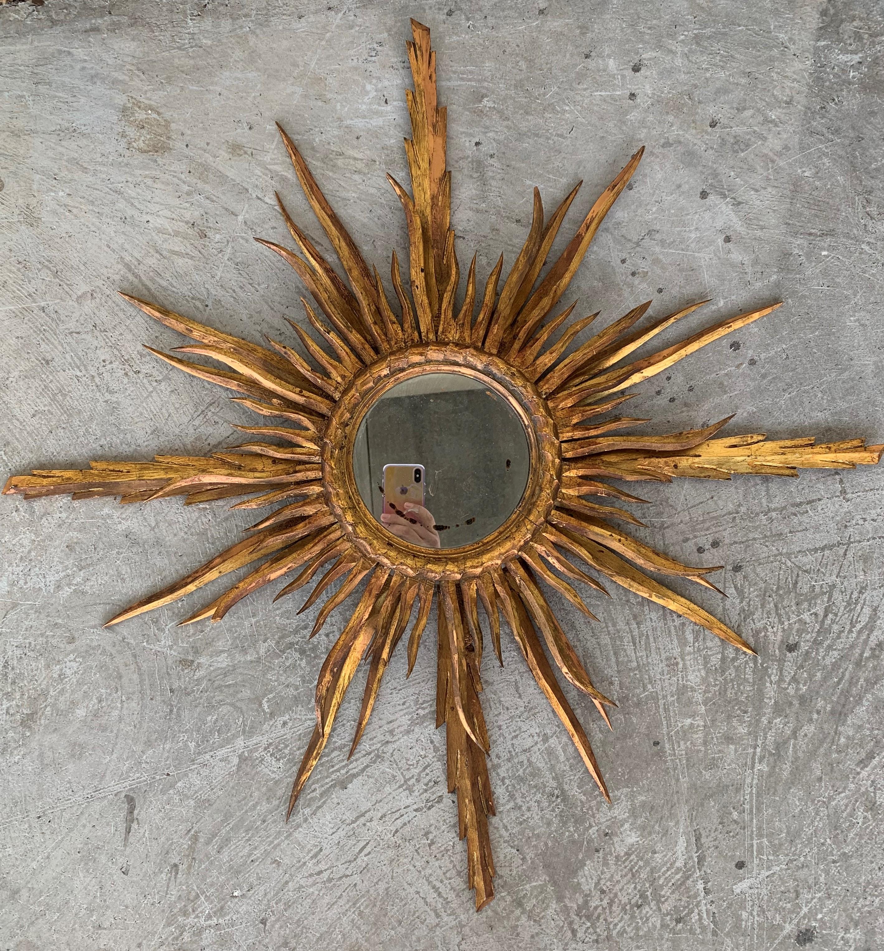 A very beautiful small sunburst mirror finely carved with 24-karat gold leaf finish. Very unusual size and interesting patina, Spain, 1930s.
Measures: Glass diameter 6.5cm / overall dimensions 30 in diameter.

