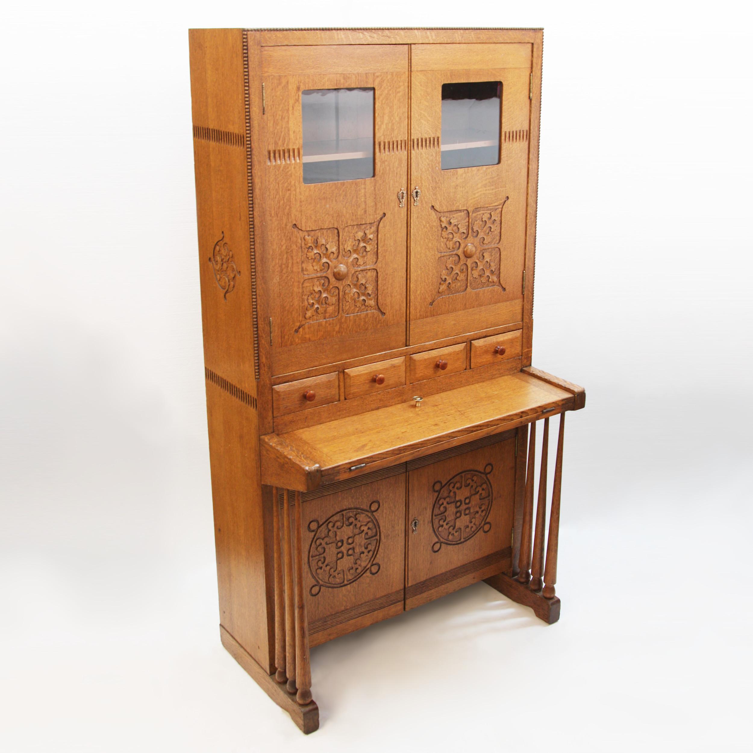 Very unusual Arts & Crafts drop-front secretary desk made in the early 20th century. Desk cabinet features solid quarter-sawn oak construction, dovetailed drawers, uniquely stylized carved motifs/details, and a distinctively transitional style. This
