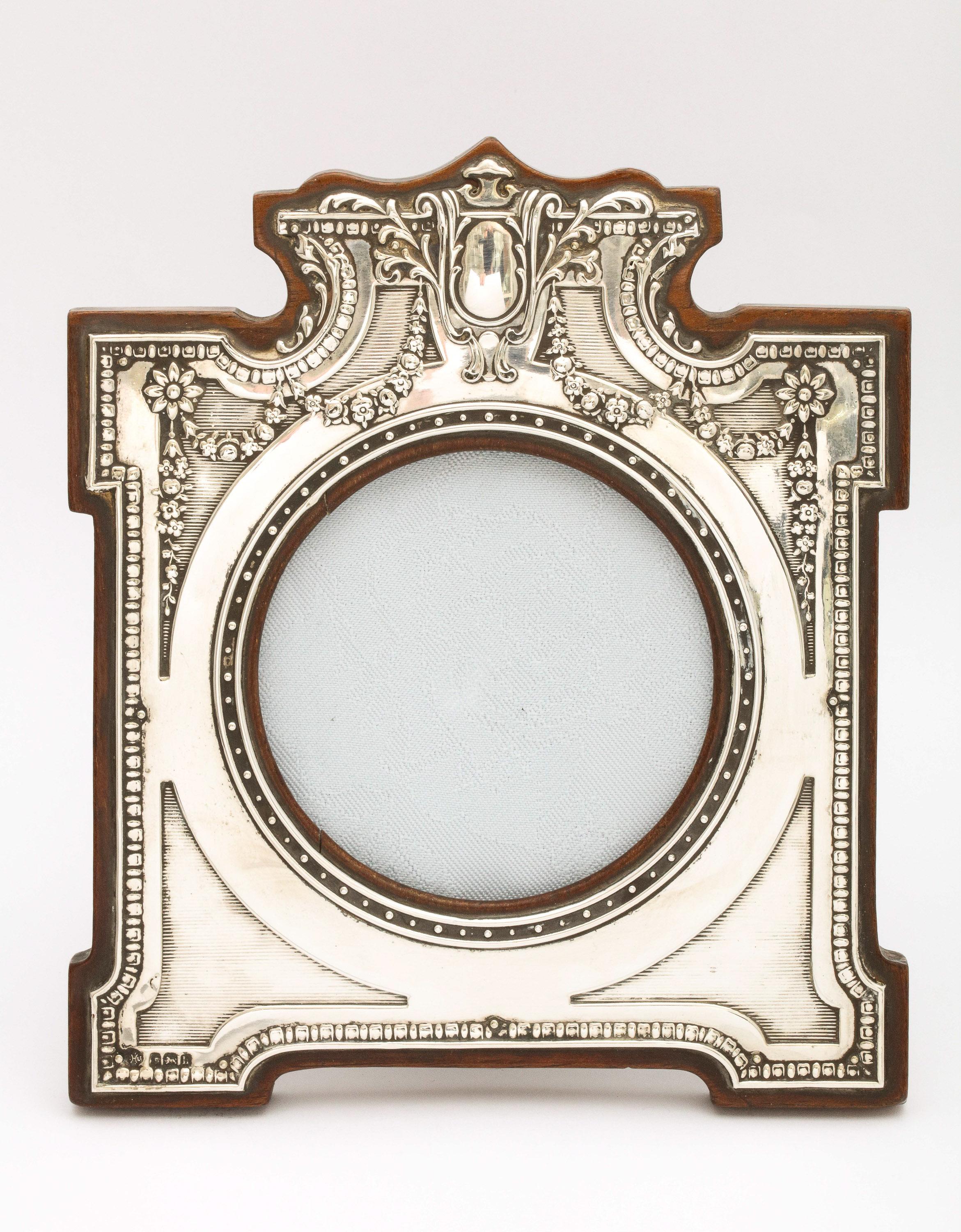 Unusual, Edwardian, sterling silver picture frame with wood back, Birmingham, England, year-hallmarked for 1907, William Hutton and Sons, Ltd. - makers. Vacant cartouche. Frame measures 7 inches high (at highest point) x 6 1/4 inches wide (at widest