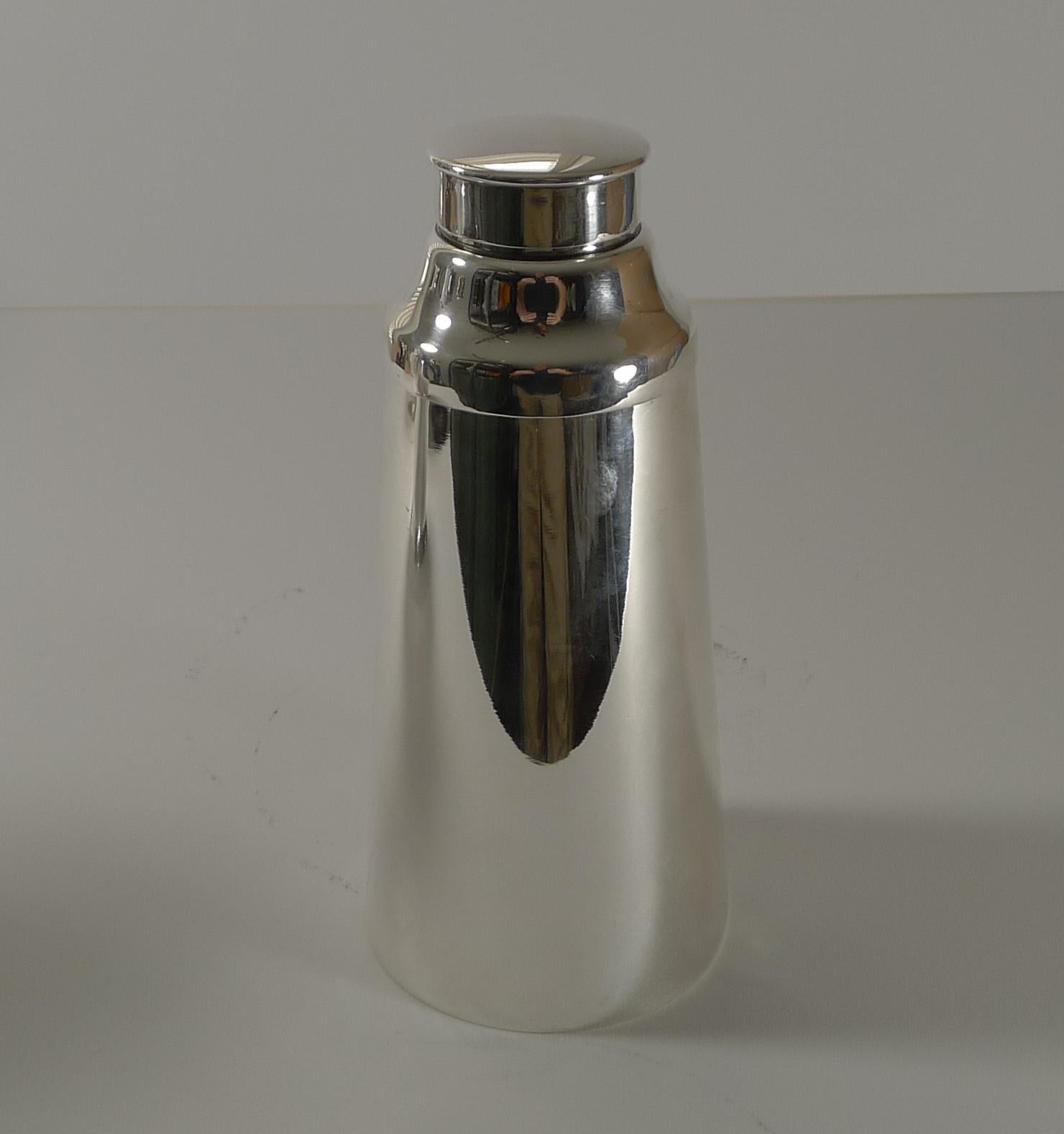 An early Art Deco cocktail shaker with a most unusual modernist conical shape, truly stylish. Made from silver plate the underside is marked with the famous trade mark for John Grinsell & Sons of Birmingham (Cupid with in a shield).

A highly