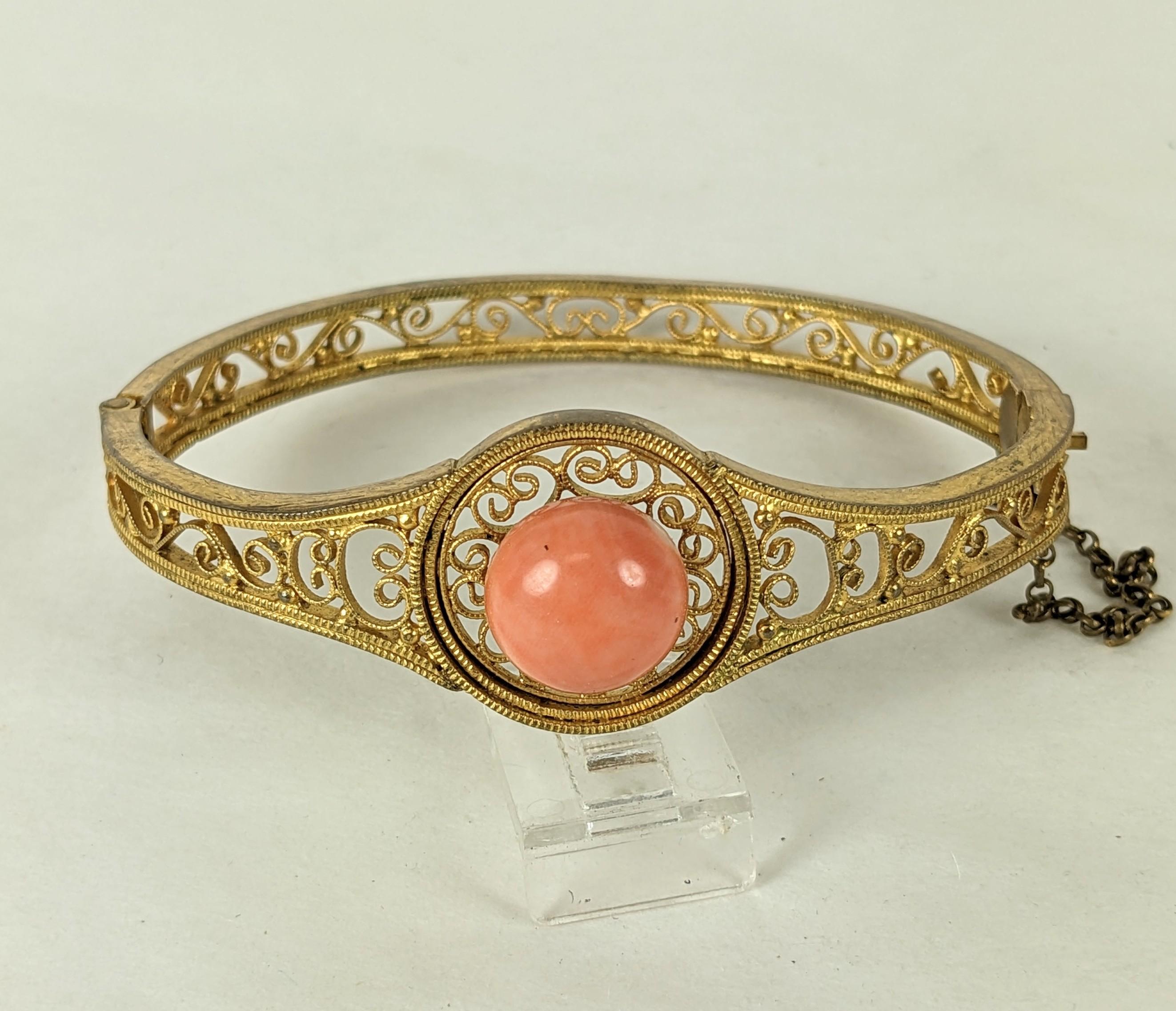 Unusual, elegant Etruscan Coral Bangle from the mid 19th Century. Hand made scroll work gold filled metal setting with genuine coral cab at center. .75