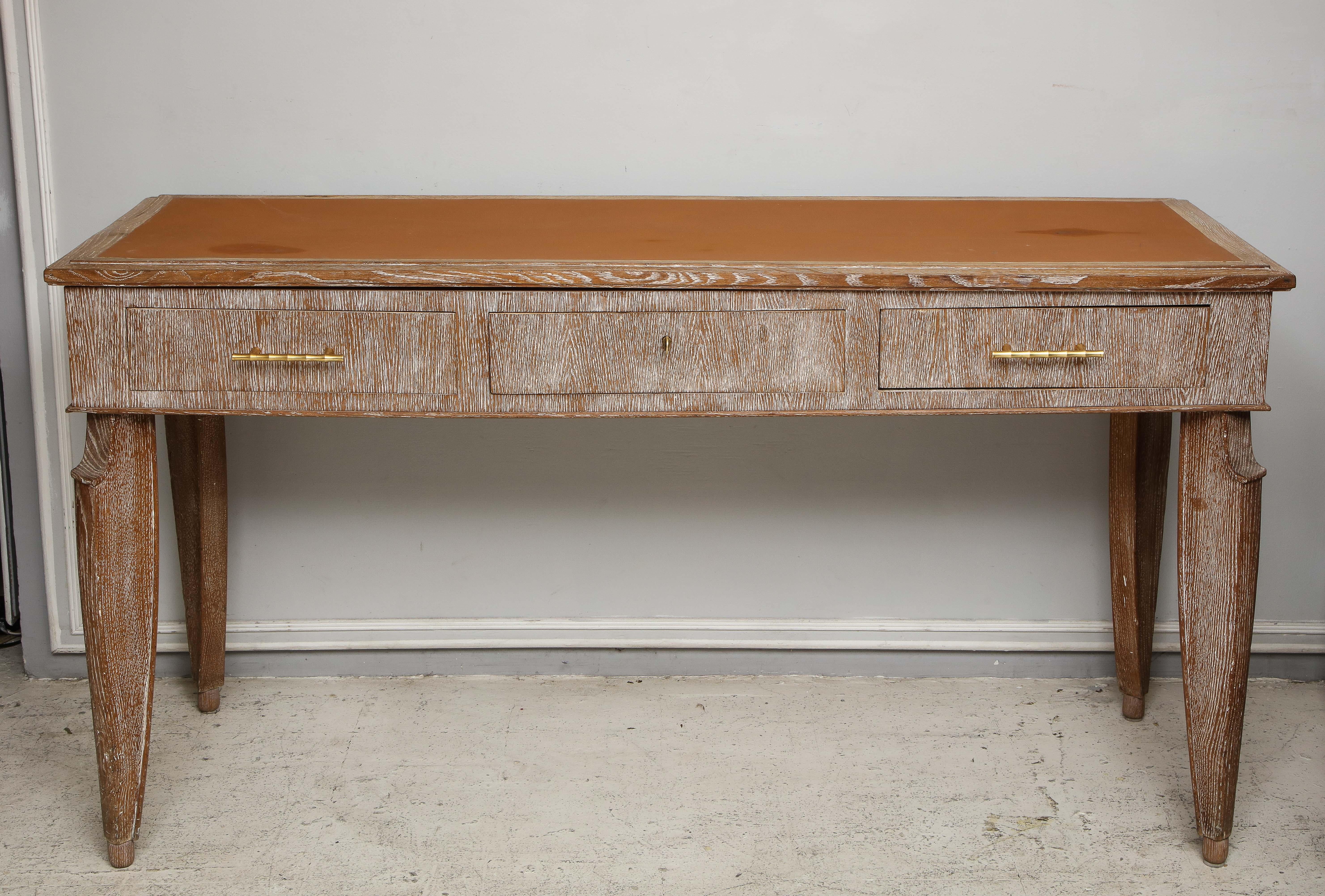 An unusual cerused oak console with leather top. The console consists of three central drawers, two drawers feature brass faux-bamboo hardware.