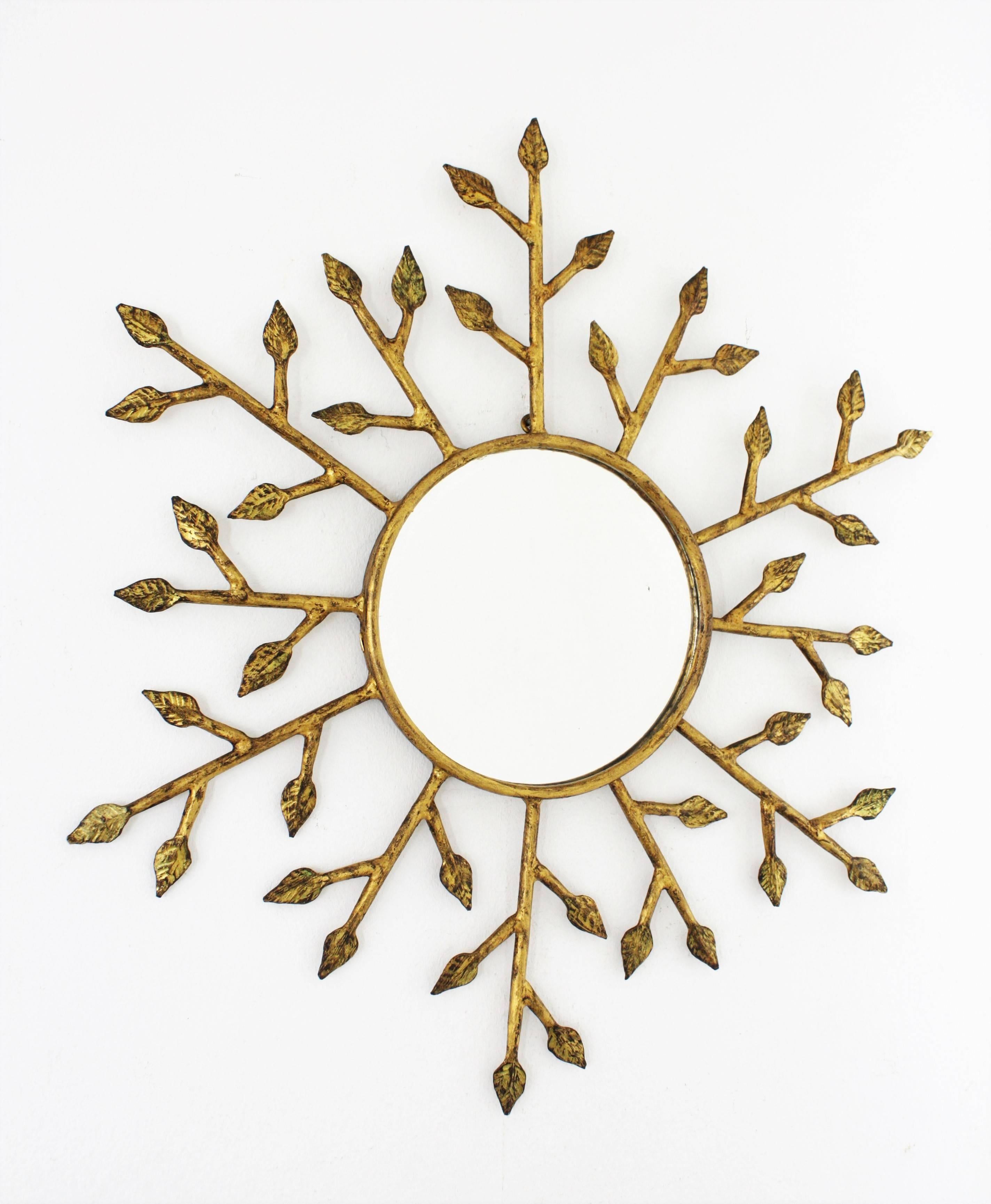 A highly decorative Hollywood Regency hand hammered gold gilt finished frame composed by branches with small leaves surrounding a circular glass, France, 1940-1950s. Glass dimensions: 19cm diameter
Available a huge collection of sunburst mirrors in