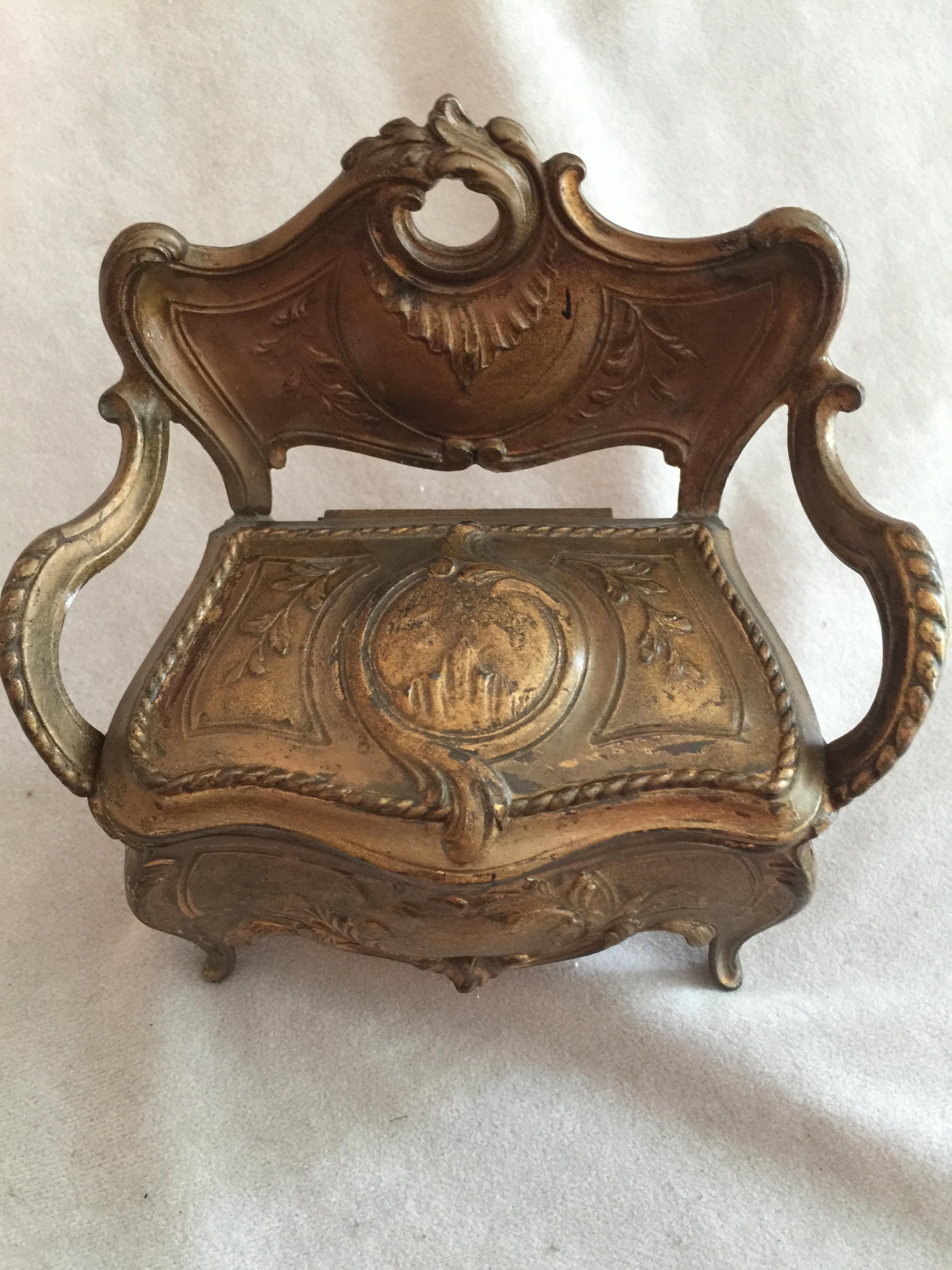 We bought a collection of miniature jewelry boxes, and this may very well be the most unusual and beautiful. It looks like a French loveseat, but the seat lifts up to reveal a jewelry box. The casting and the detailing are very fine. The inside has