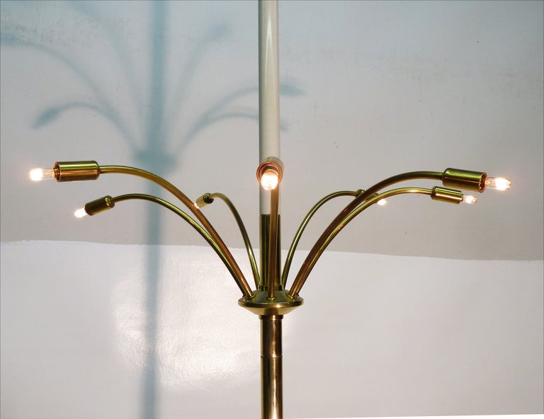 This rare light fixture in the manner of Jacques Adnet features expandable vertical tension rods which affix to the ceiling and a lower surface such as a table or the floor effectively making it a standing chandelier. The piece has a 12