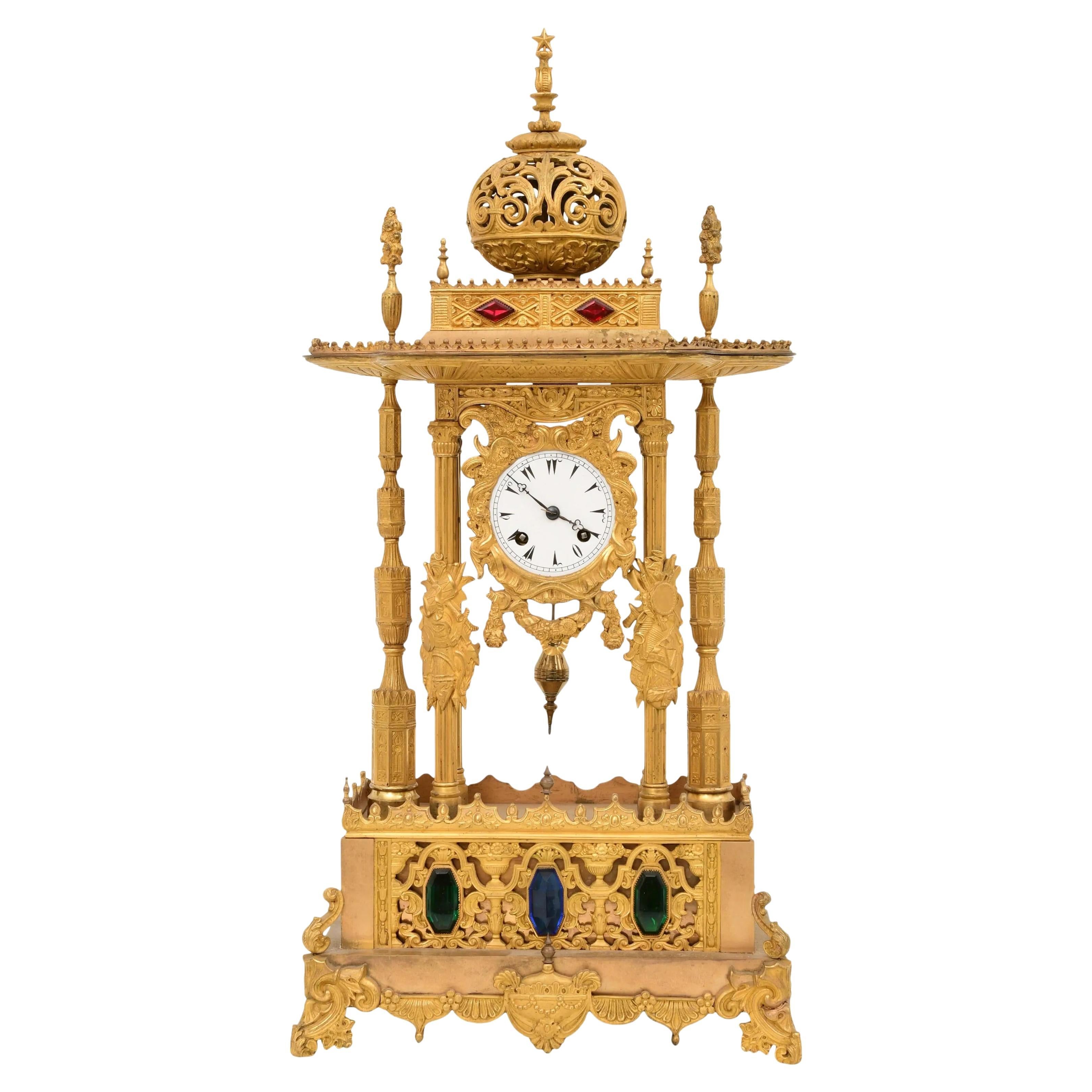 Eine ungewöhnliche französische Louis-Philippe-Uhr mit Ormolu und Juwelen, die für den osmanisch-türkischen Markt hergestellt wurde, um 1840.

Das verschnörkelte Gehäuse, an dem ein Blumenband hängt, wird von kannelierten Säulen flankiert, an