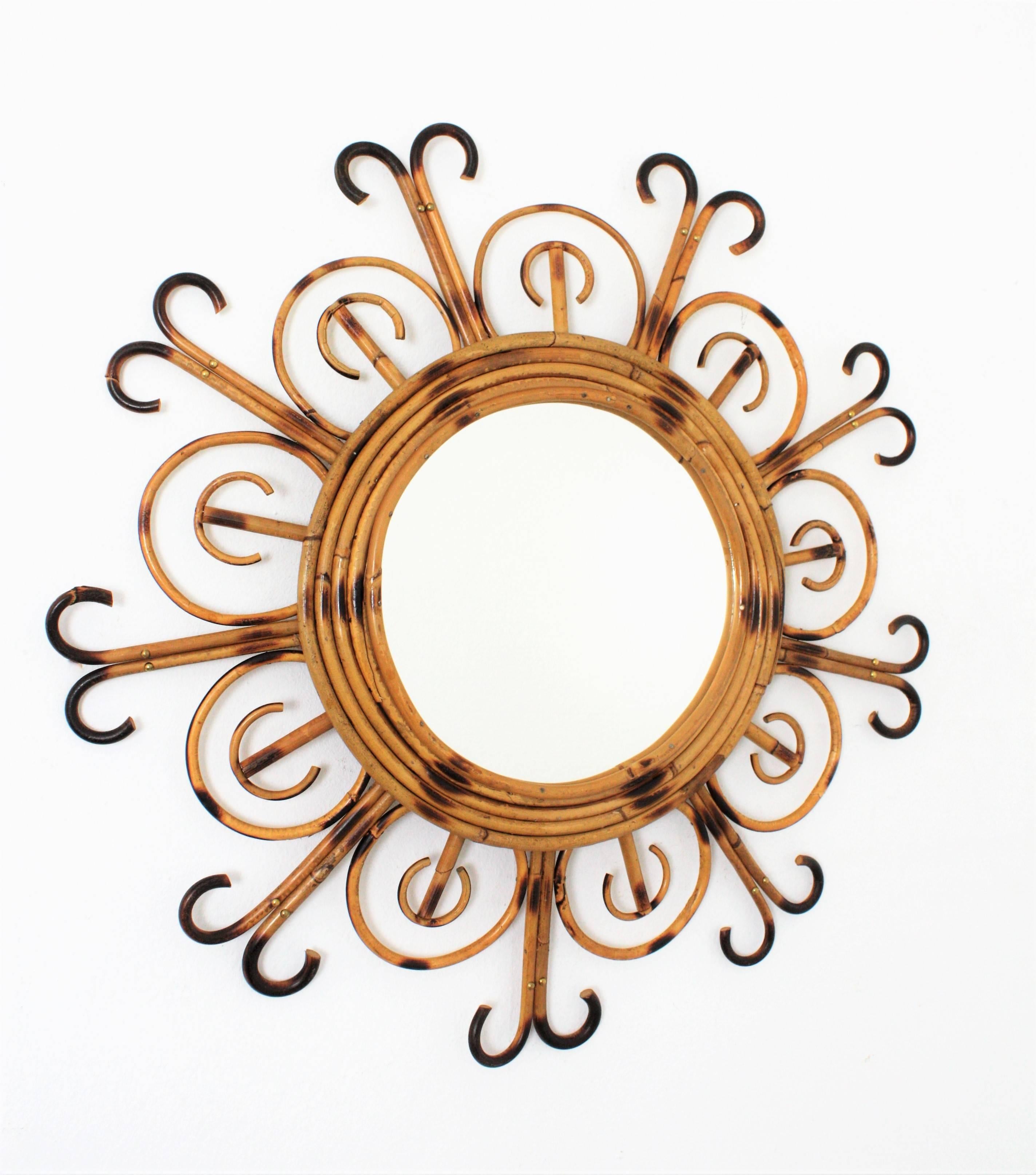 A highly decorative flower shaped rattan and bamboo mirror with pyrography decored with cane petals and curved ended rays. This piece has all the taste of the French Mediterranean Coast. Manufactured in France at the 1950s. Dimensions of the glass:
