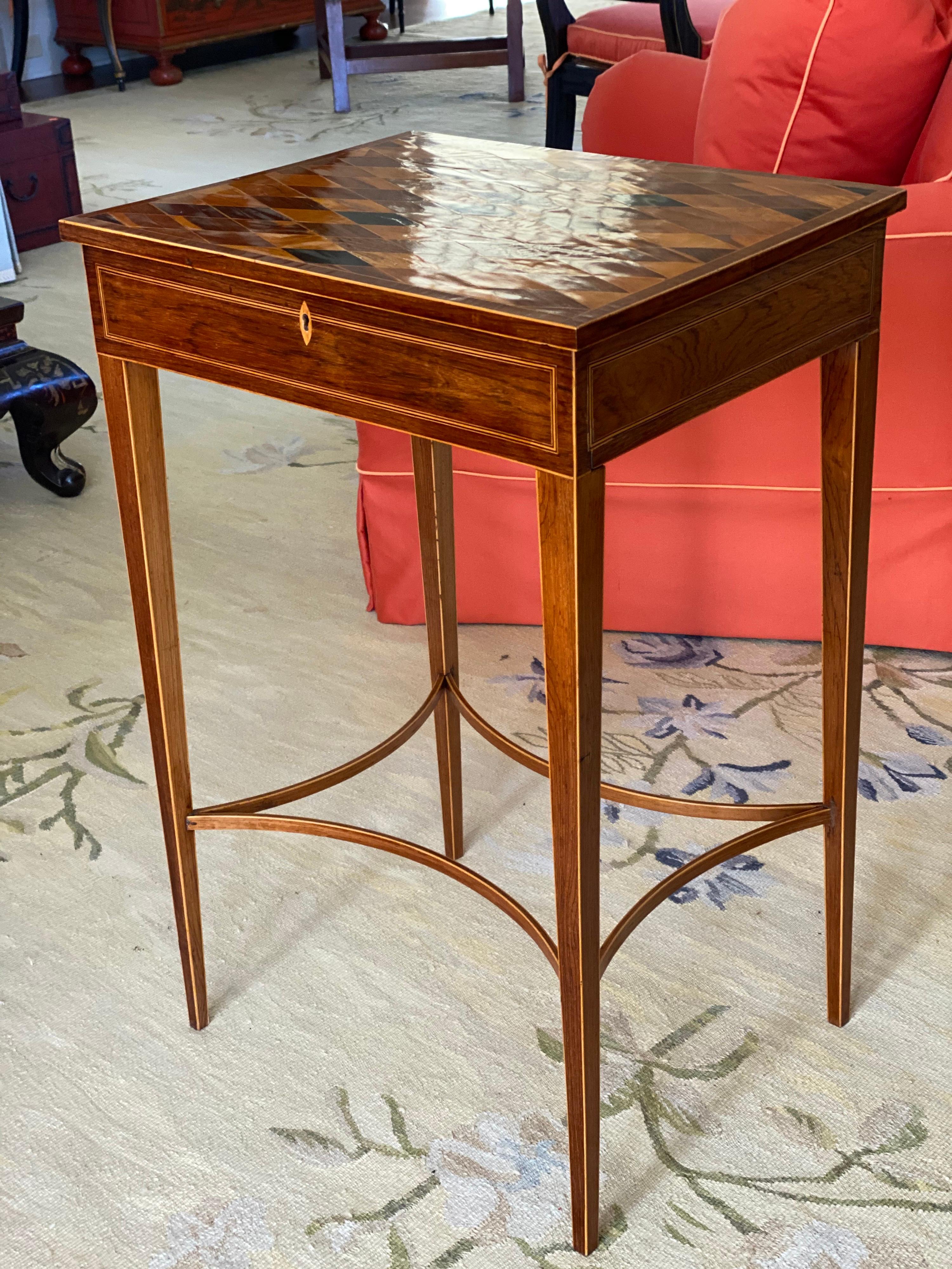 Unusual George III inlaid rosewood and specimen wood parquetry work table, circa 1800.
The hinged rectangular parquetry top inlaid with specimen woods in a lattice pattern and over a simulated frieze drawer fitted with a keyhole and raised on