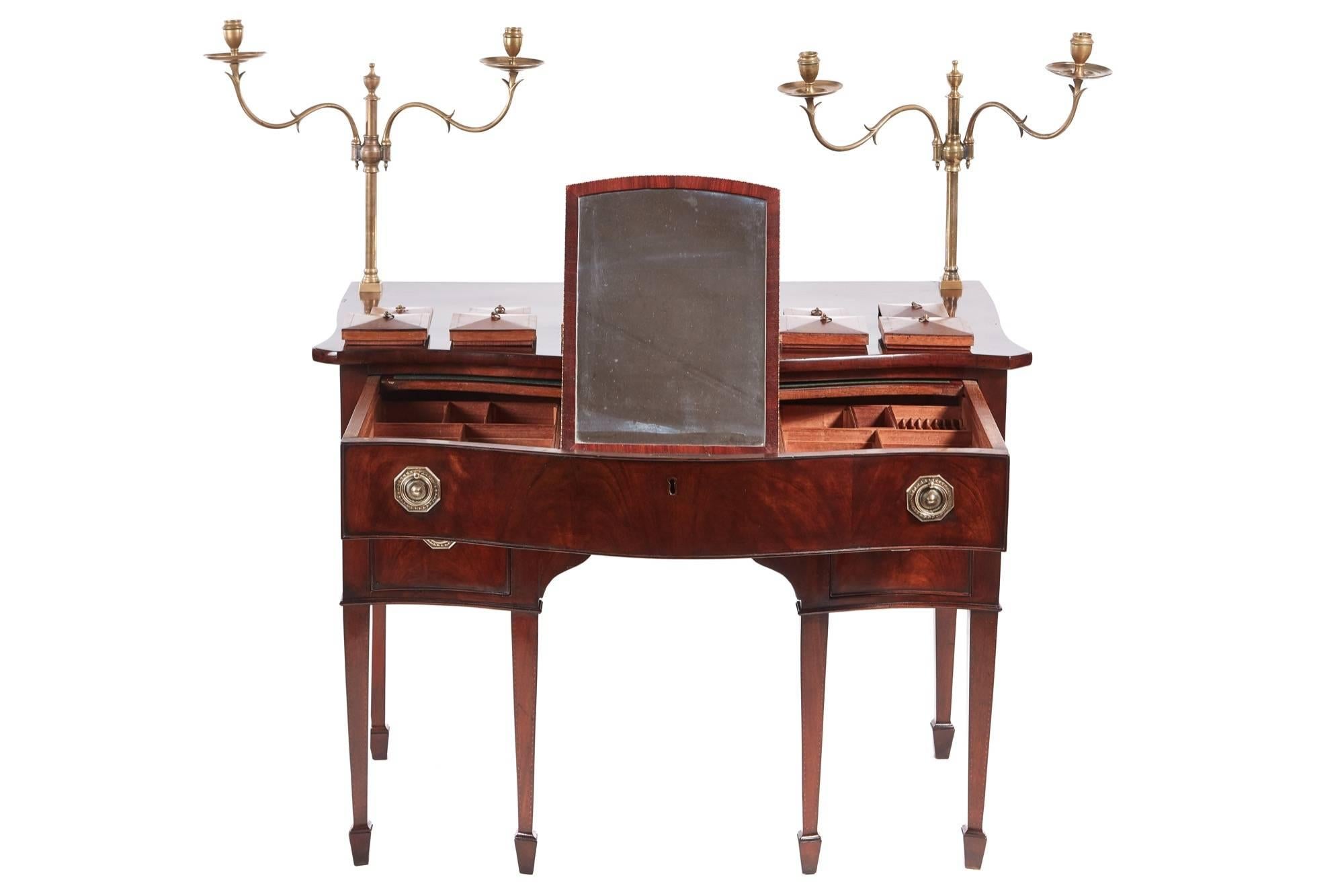 Unusual George III mahogany serpentine fronted dressing table, with a pair of brass candelabrum, lovely mahogany top, one long serpentine drawer fitted with boxes, brushing slide and a folding mirror, two small drawers all with original brass