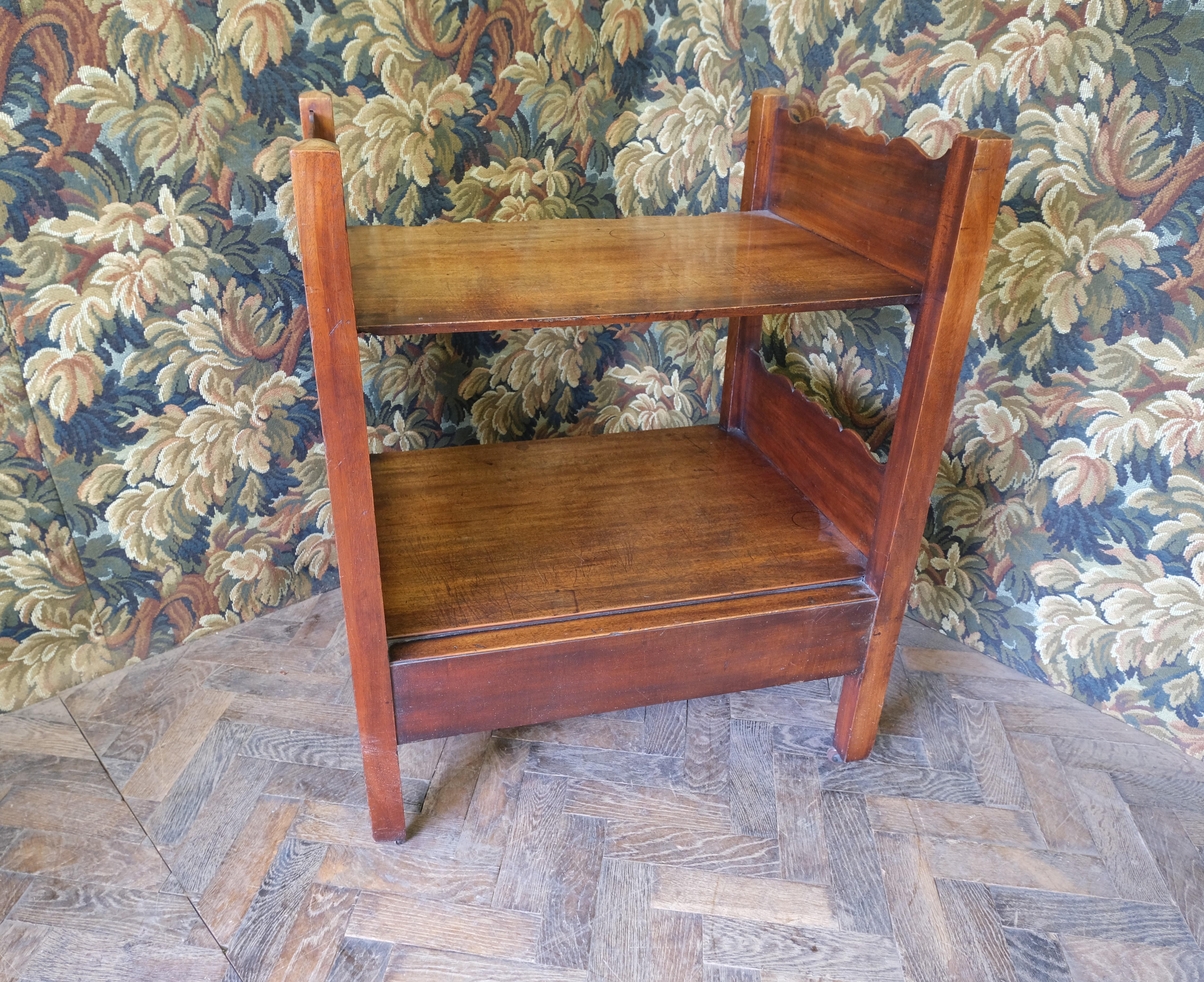 Hutton-Clarke Antiques proudly presents a unique Georgian mahogany table stand/whatnot, circa 1760. Crafted from solid mahogany with original axe head handles and double serpentine-shaped sides, it features a fixed shelf and wide country house