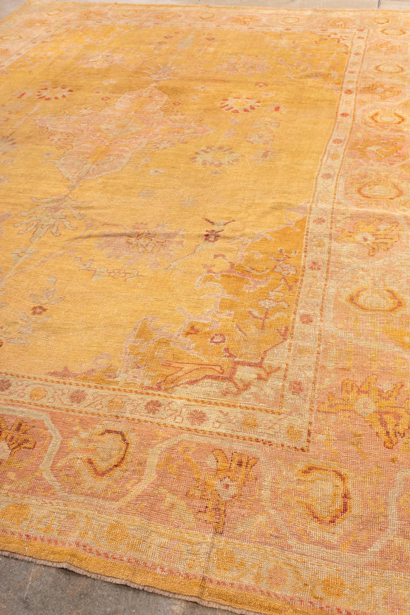 The unusual old gold field shows a central, sand geometric medallion with palmette pendants and four supporting zebra palmettes. The rug features deep gold corners and a pale green border with faceted meander and palmettes.

Rug Size
10'4x13'10