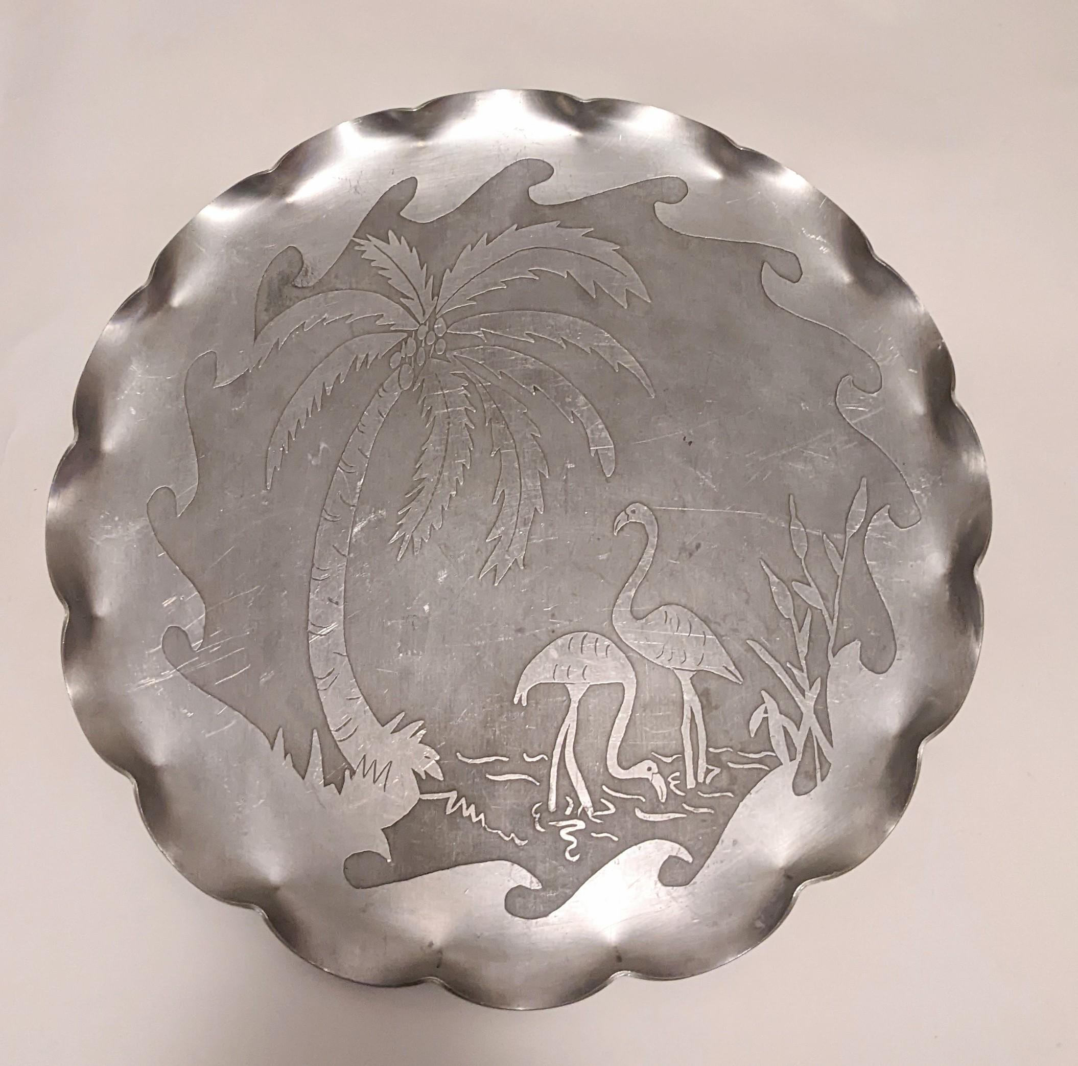 Unusual hand made folk art tray from the 1950's in aluminum with etched and incised tropical theme of flamingos in palm trees. Great serving and conversation piece signed by woman artist 1950. Edges are gently scalloped for interest.