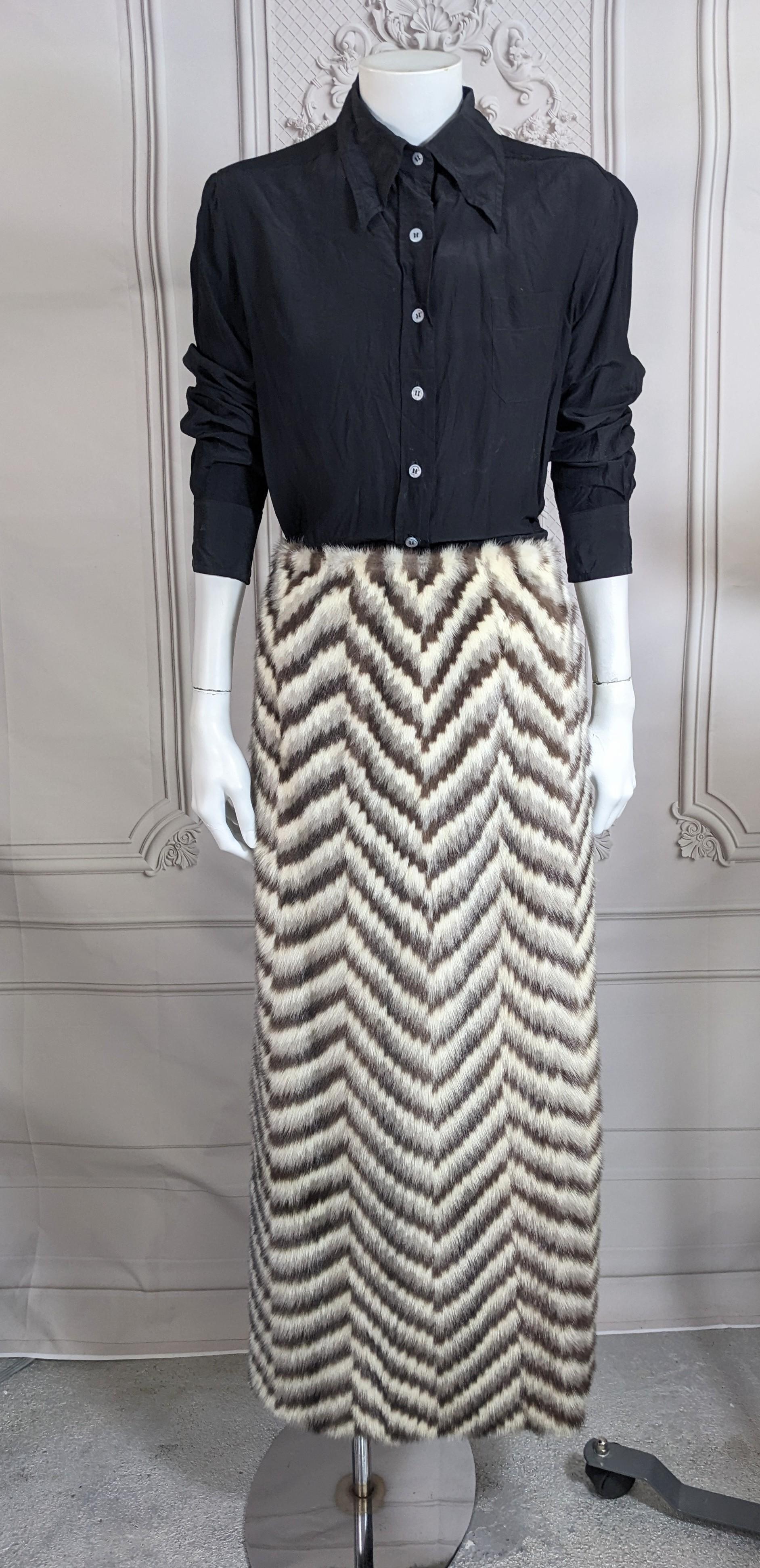 Inhabituelle jupe d'hôtesse des années 1970 à motif chevron en vison intarsia. Des bandes de vison doux dans différents tons forment des motifs à chevrons sur la jupe longue à ligne légèrement A. Entrée zippée au dos. 
Commande sur mesure,