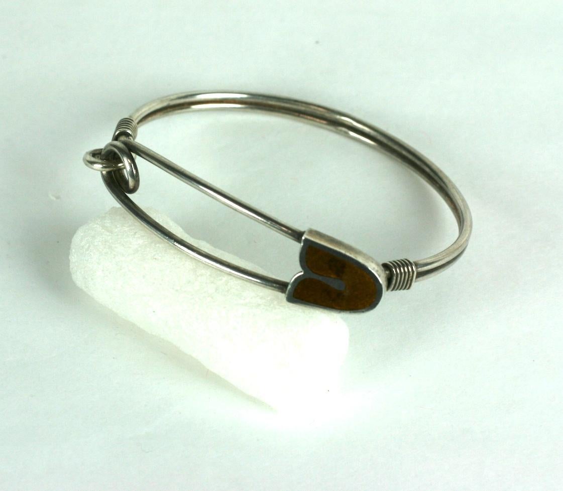 Insolito braccialetto con spilla di sicurezza in argento con decorazioni in smalto marrone. Realizzato in Italia intorno agli anni '70 in argento 800. Si sgancia con un ingegnoso meccanismo di aggancio interno. Super qualità.
Si adatta comodamente a