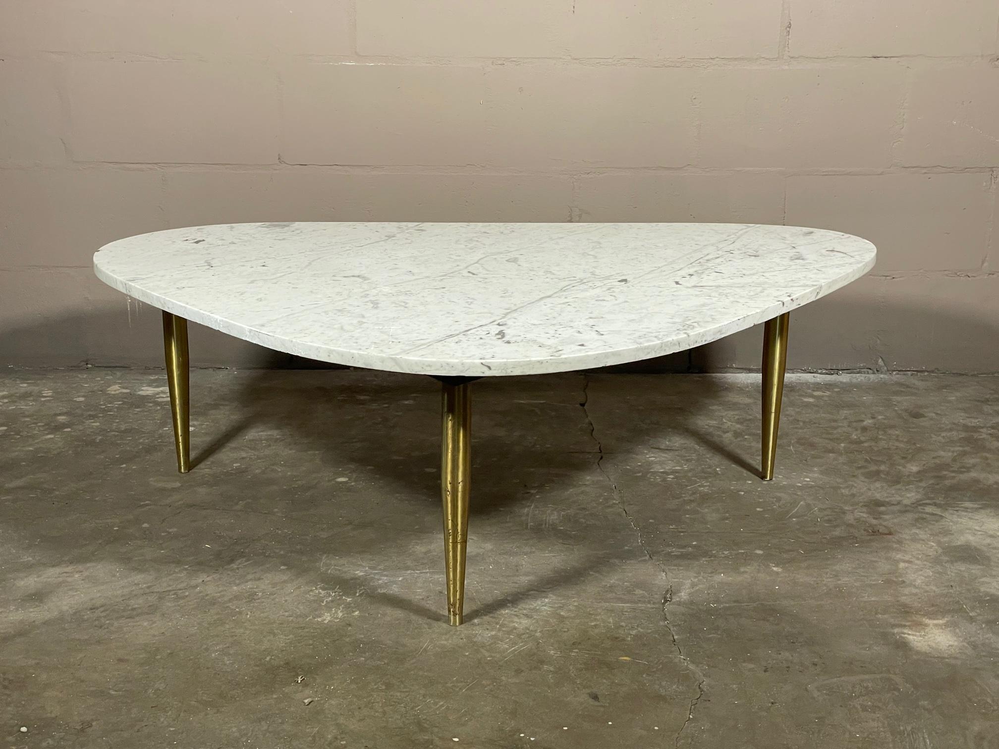 An unusual Italian table with brass legs, Carrara white marble top with an interesting-triangular, biomorphic shape.