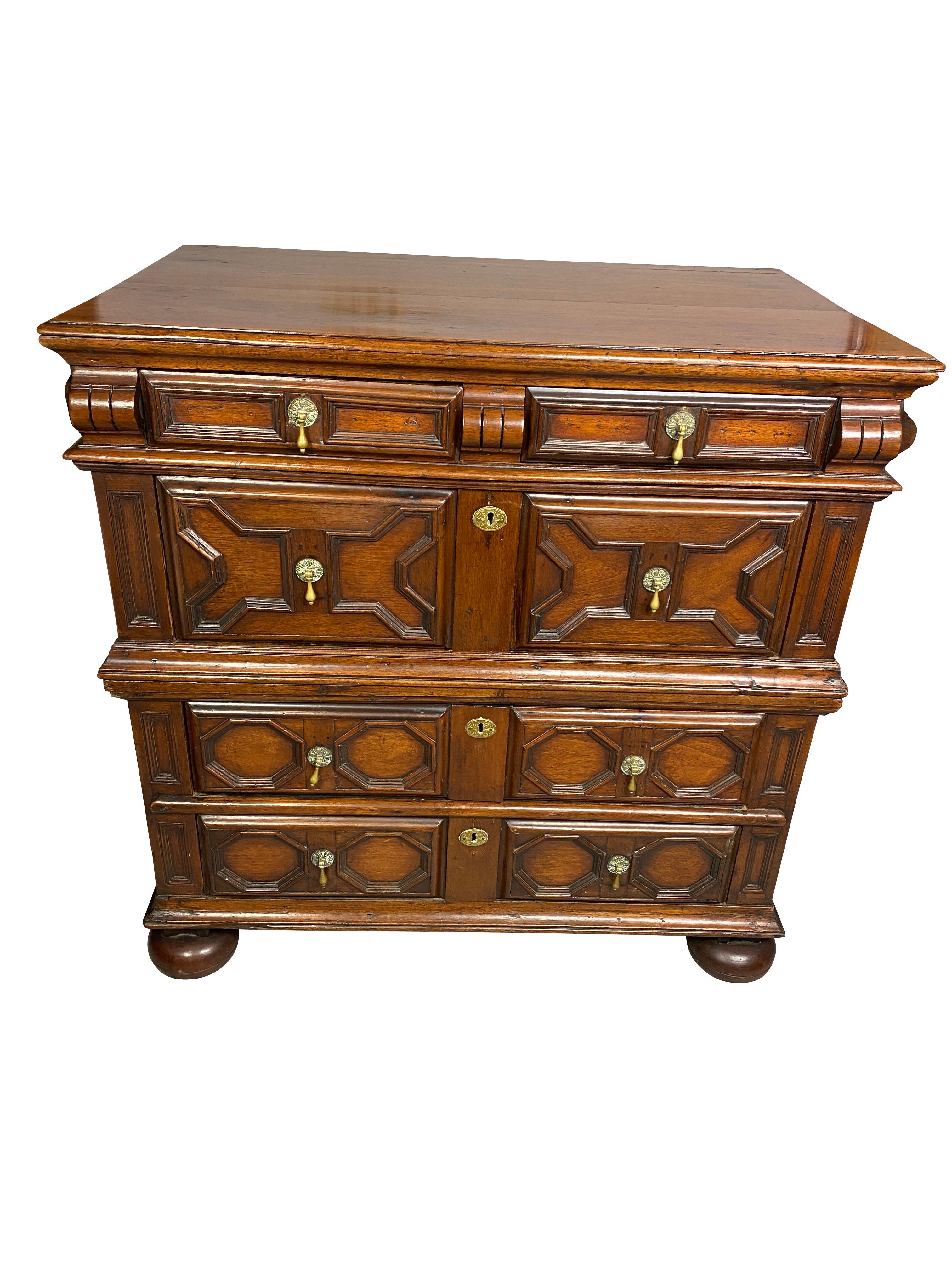 This form is usually oak. With rectangular top over a long shallow drawer over three geometric paneled drawers, sides paneled, bun feet. This chest is in two parts for easy moving and getting into tight spots.