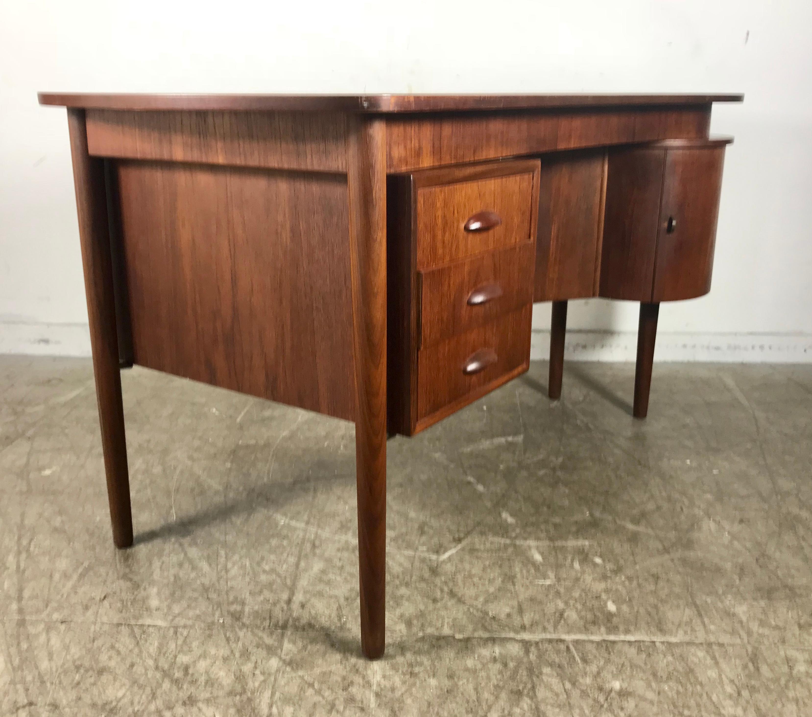 Unusual kidney teak desk by Kai Kristiansen, double-sided, door and bookcase. Stunning round right door with shelf. Beautiful warm teak tone. Amazing quality and construction. Hand delivery avail to New York City or anywhere en route from Buffalo