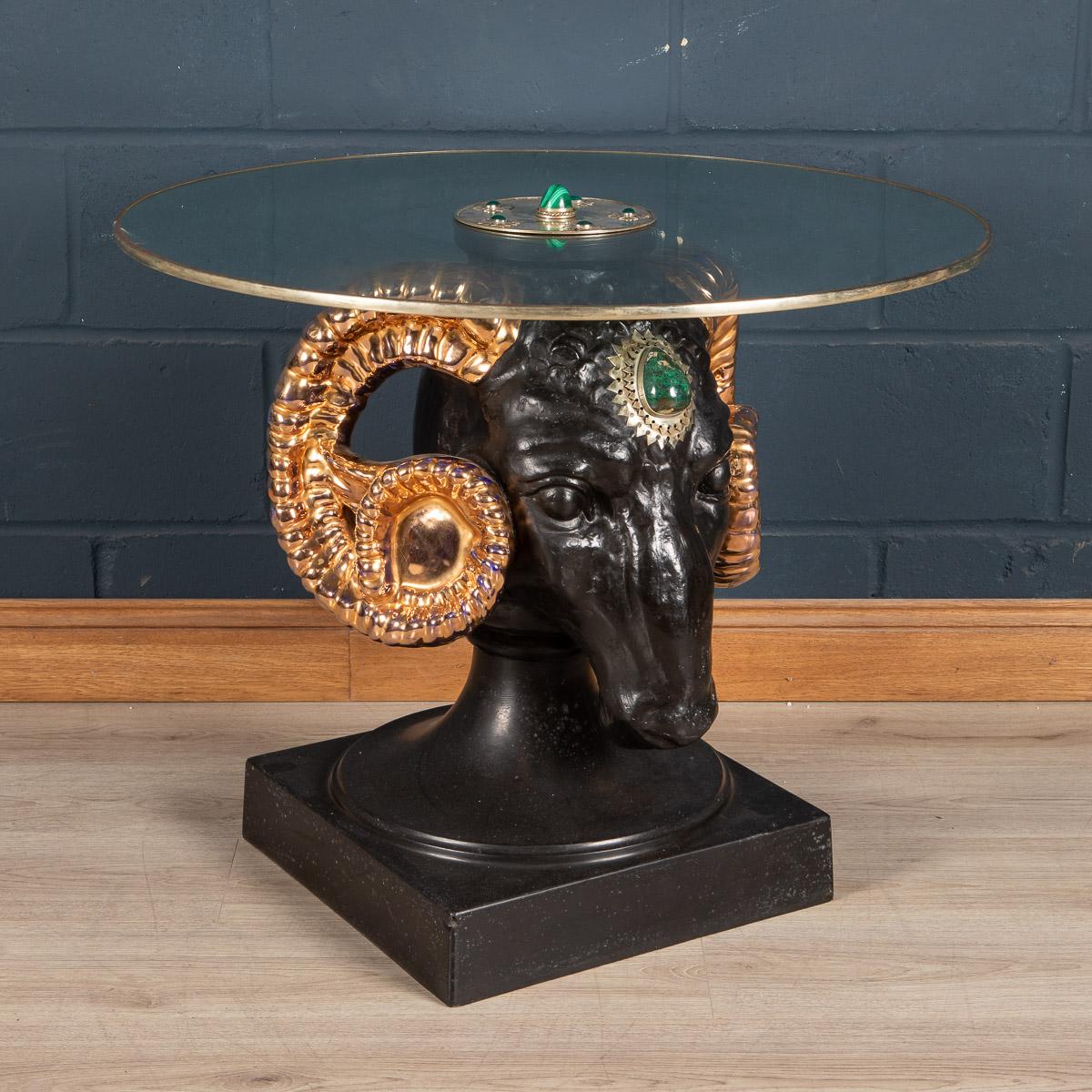A coffee table by Anthony Redmile, London, circa 1970. The base of the table fashioned from composite painted head of a ram, the central circular plaque inlaid with hardstone cabochons signed Redmile, London to the centre. Anthony Redmile burst into