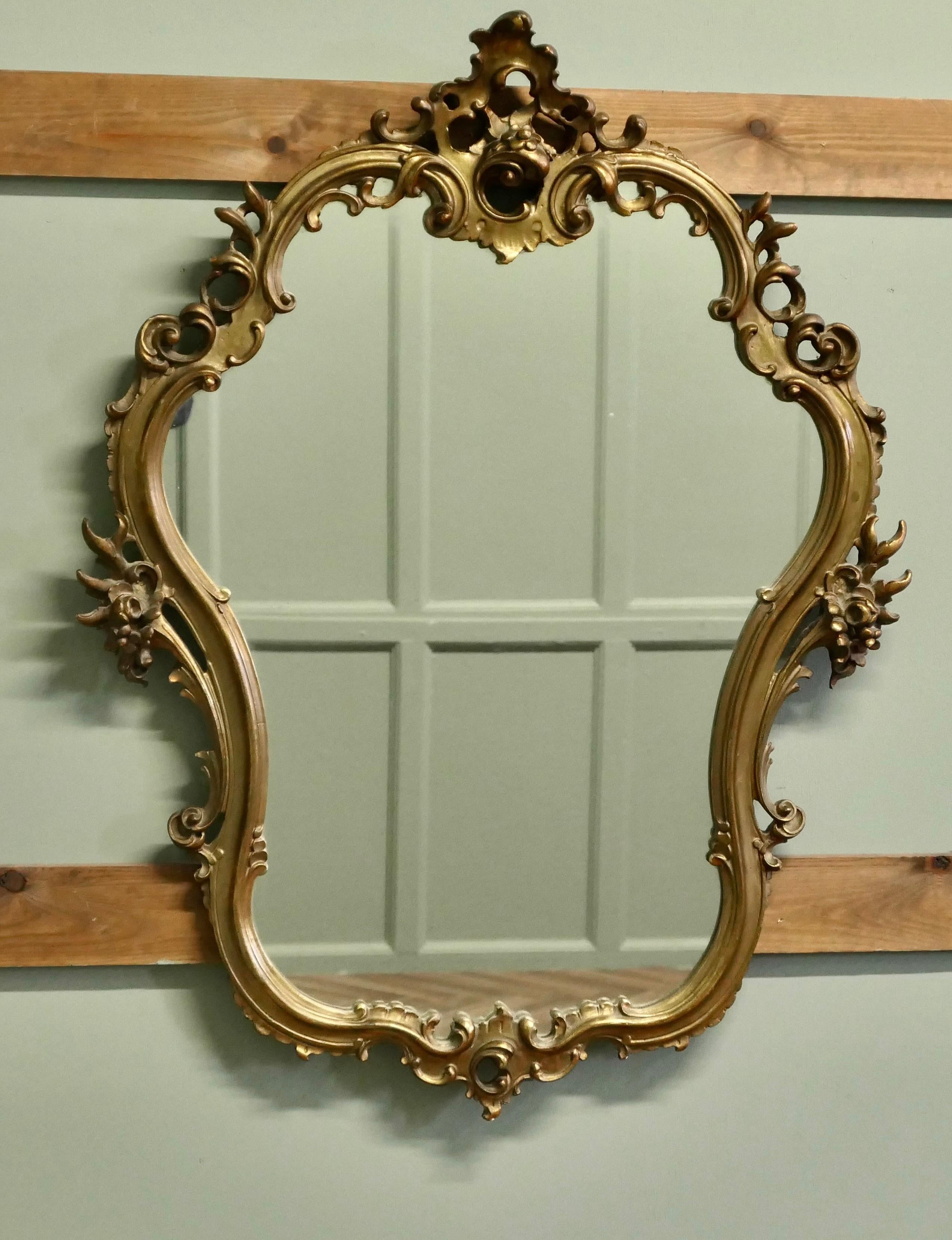 Unusual Large Rococo Style Gilt Wall Mirror

The Mirror has an elaborately shaped aged gilt 3” Frame in the Rococo Style, with shells and scrolls and flowers decorating around the frame
This is a very superior quality 20th century craftsman made