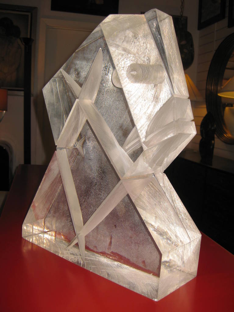 This Lucite sculpture features an angular, geometric form made more interesting by structural details found within the Lucite. With a closer look, one can see intersecting lines and shapes within the Lucite piece, as well as a cylindrical hole
